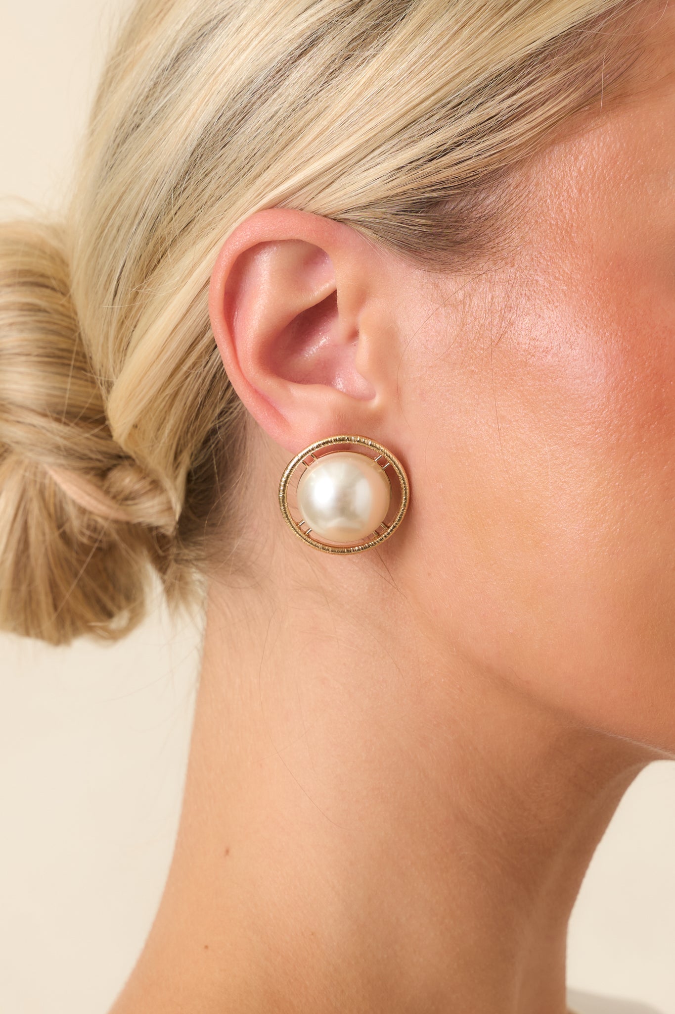 Classic gold-tone earrings with smooth faux pearl centers surrounded by a textured circular halo and secure post backs.