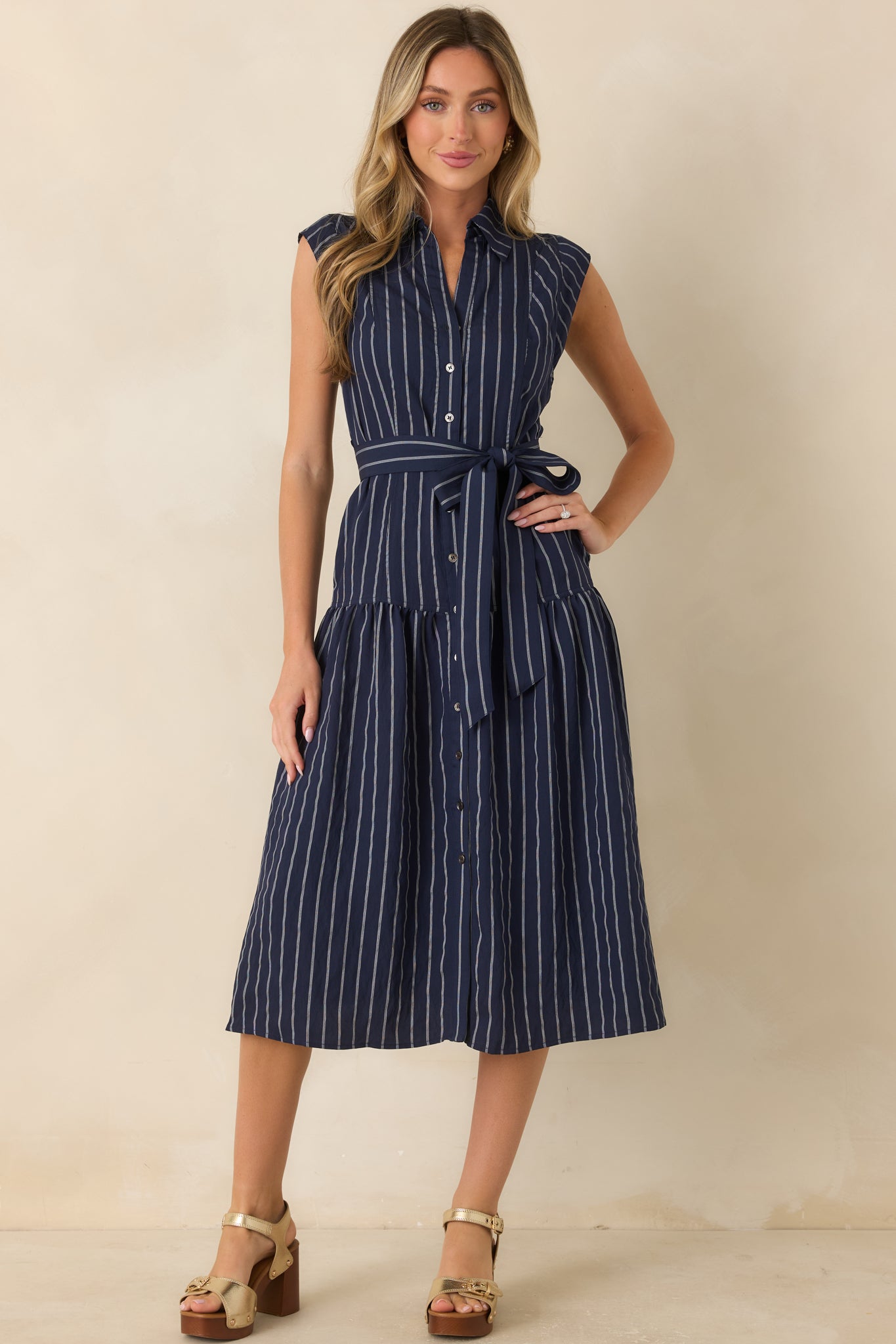 Classic striped midi dress showcasing a functional button front, drop-waist seam, side pockets, and flowing silhouette.