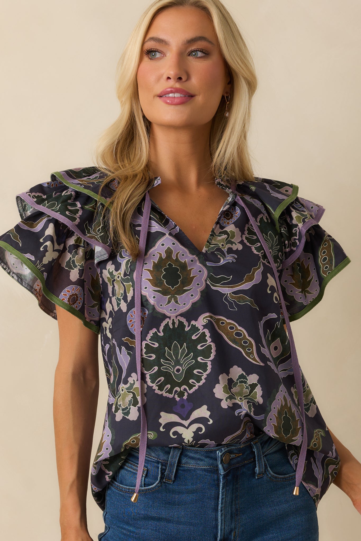 Close crop of neckline and upper chest, emphasizing ruffle trim and self-tie tassels.