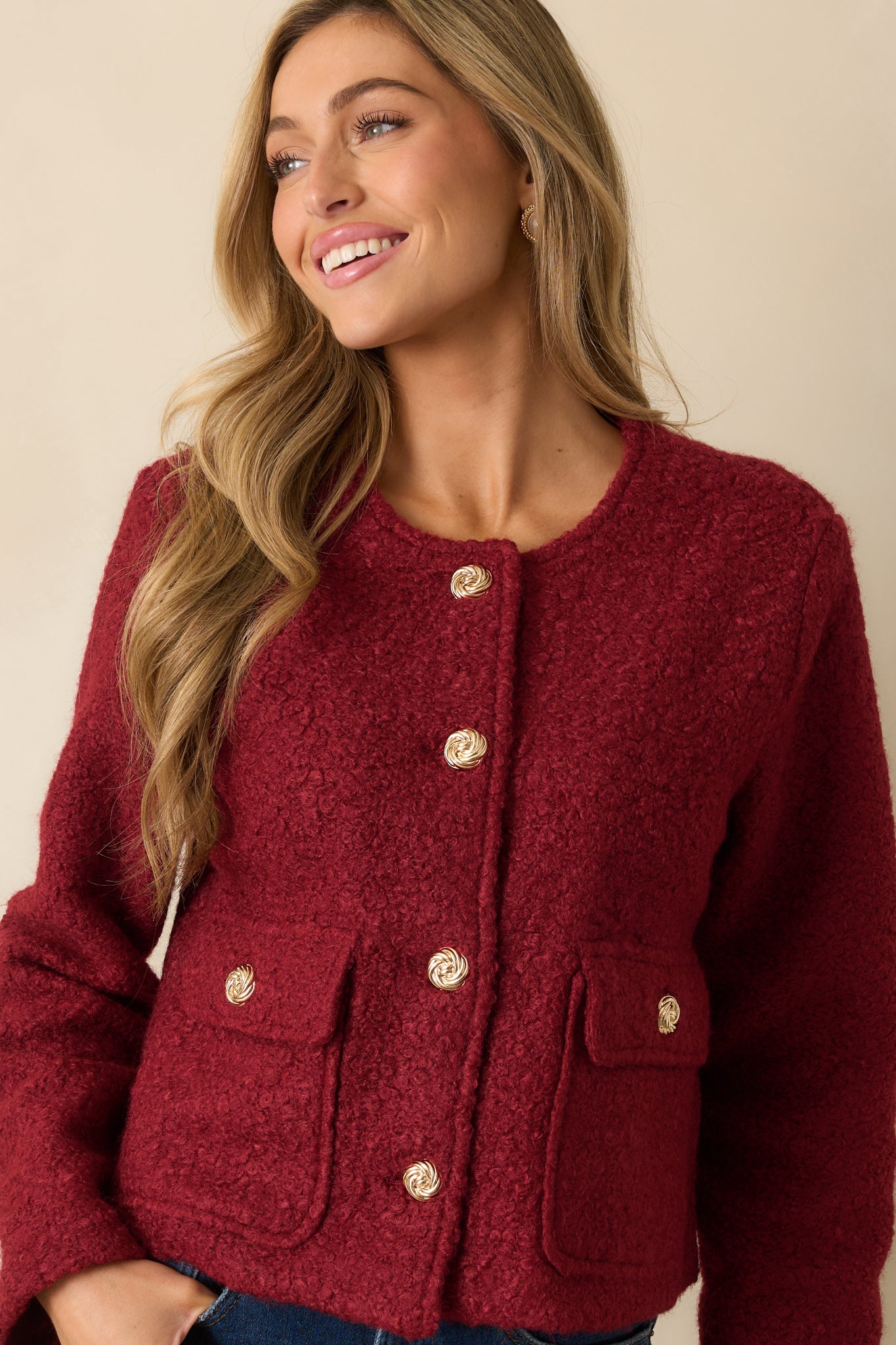 Close crop emphasizing the textured bouclé fabric and decorative gold button closures at the front.