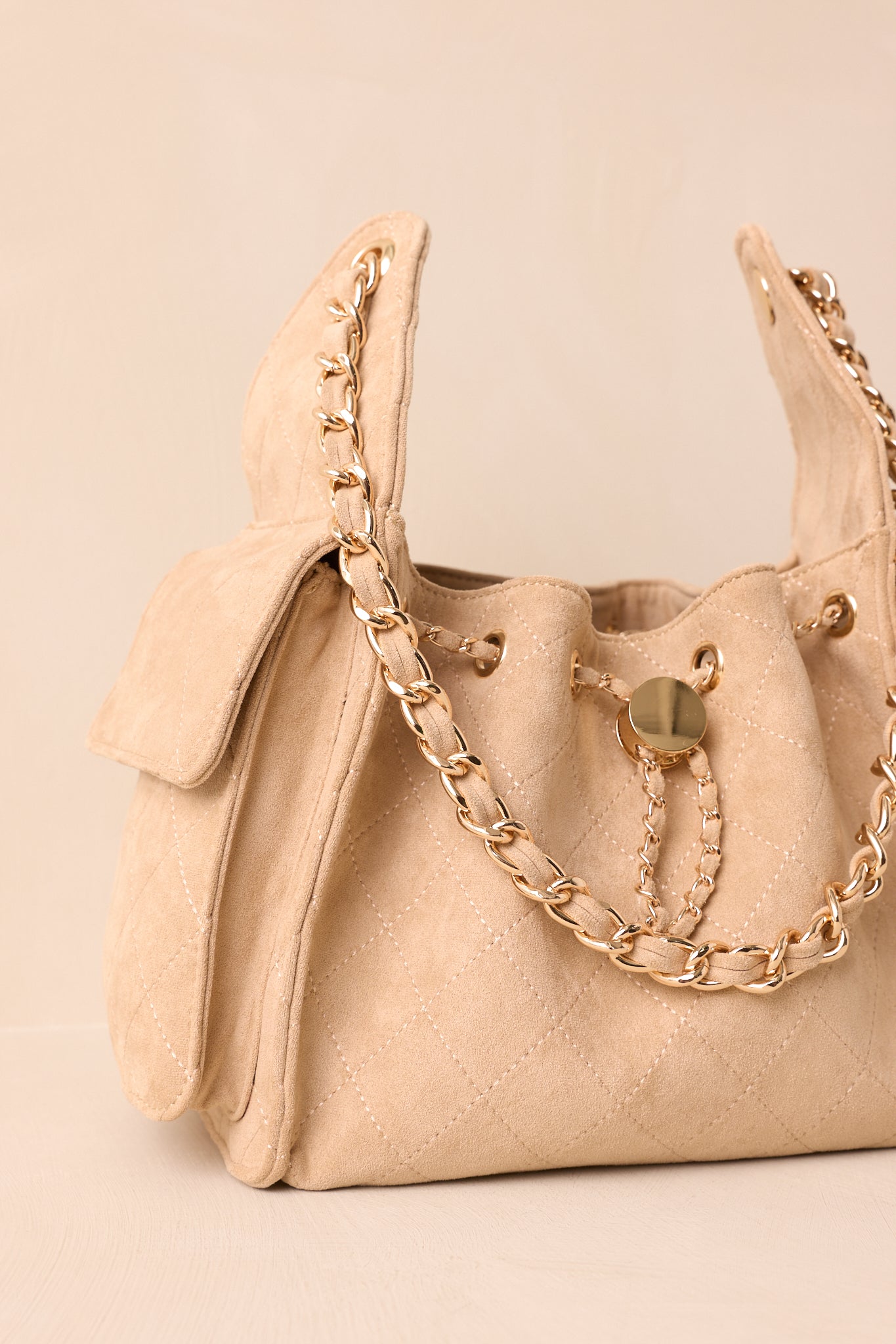 Close crop of the purse showing quilted texture and gold grommets along the drawstring.