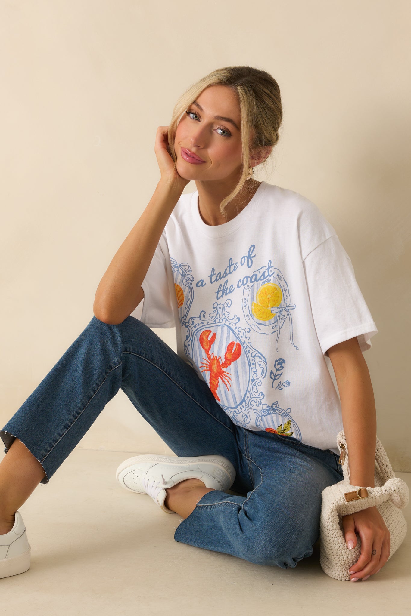 Close crop of the white tee’s front midsection showing the relaxed fabric drape and part of the coastal graphic design.