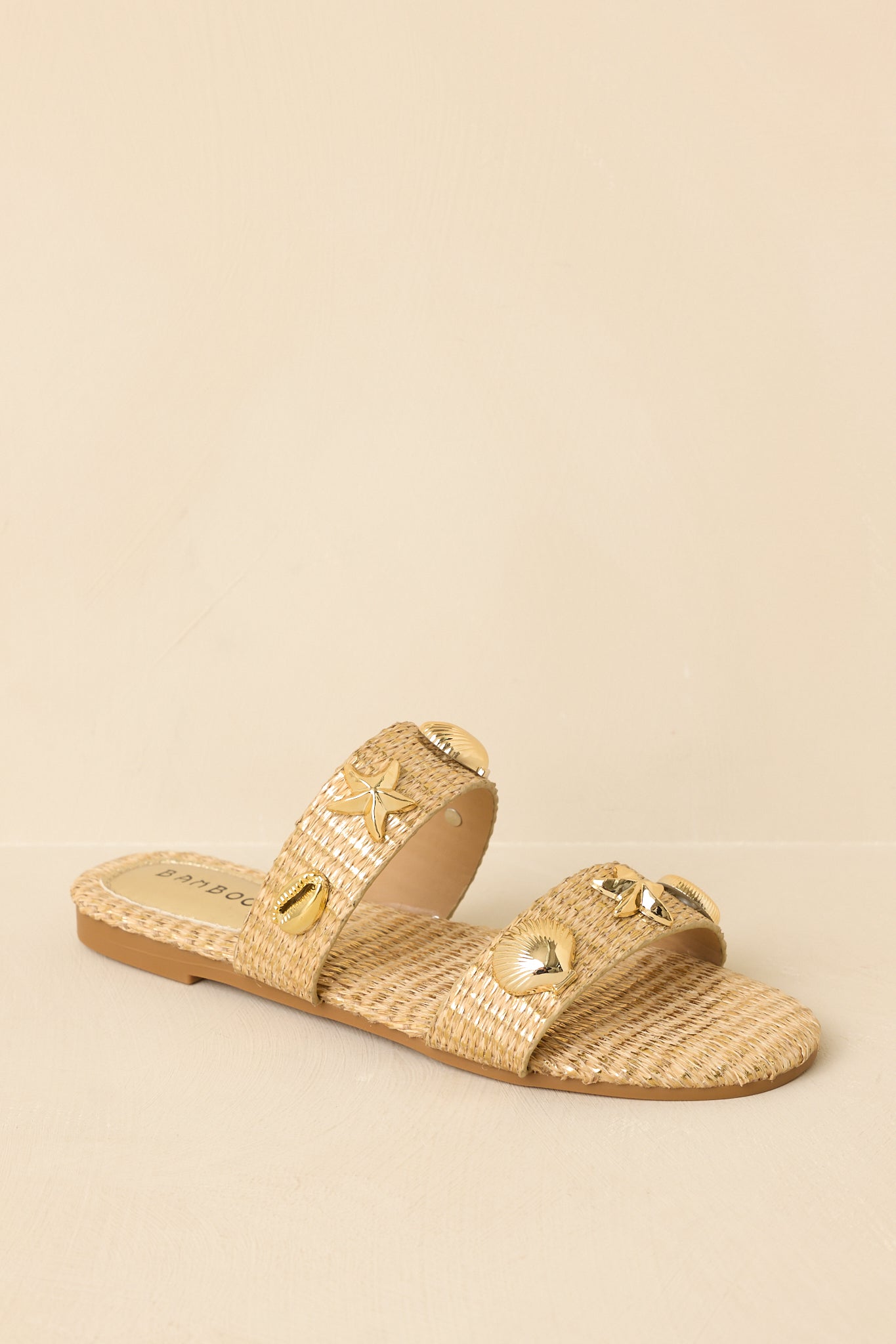 Close cropped angle highlighting the textured raffia straps and metallic shell and starfish embellishments.