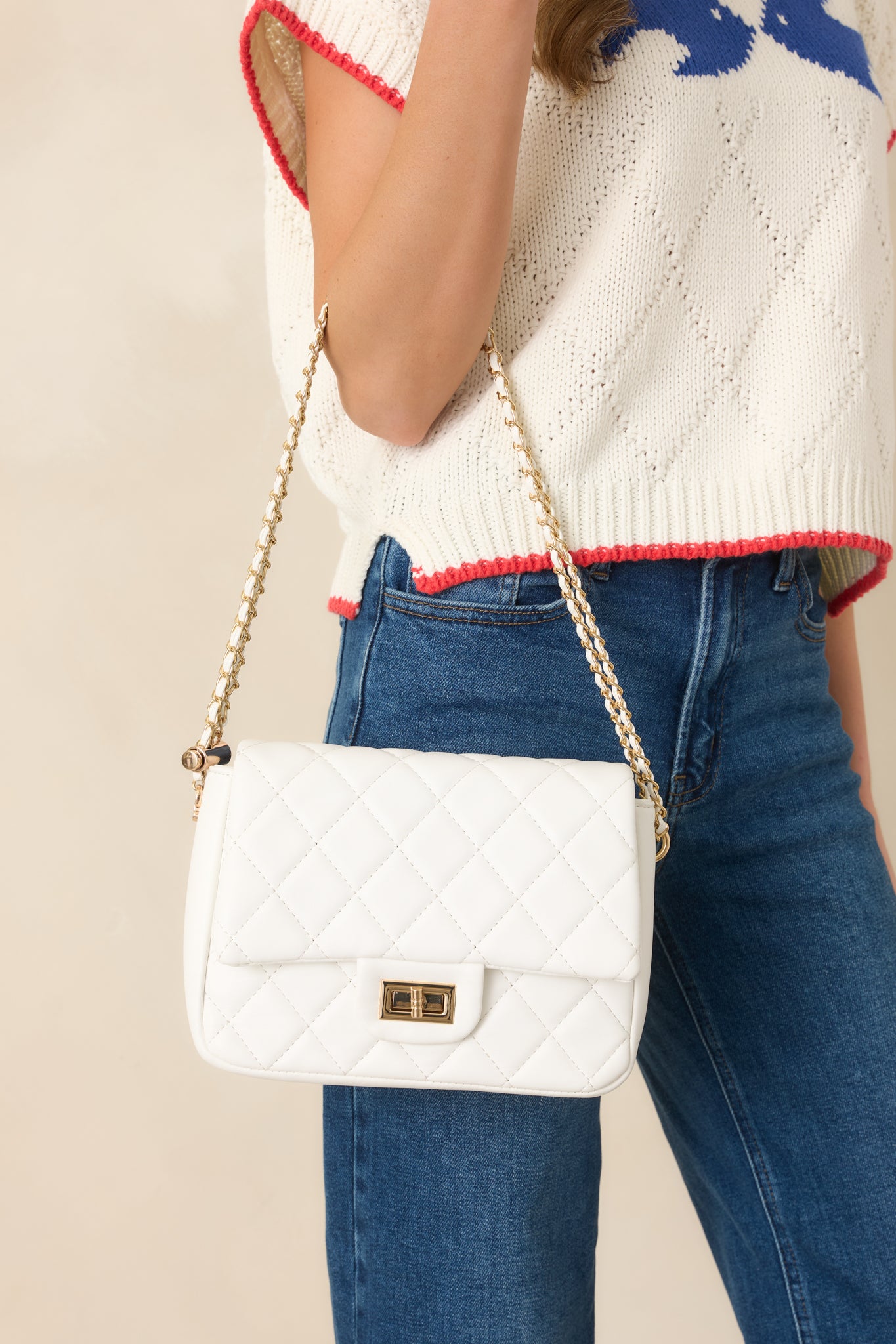 Close cropped angle of white handbag emphasizing quilted design and polished gold hardware accents.