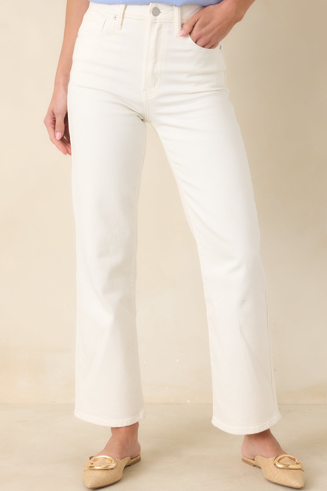 Close cropped angle of white high-rise jeans emphasizing the waistband, belt loops, and front pocket stitching.
