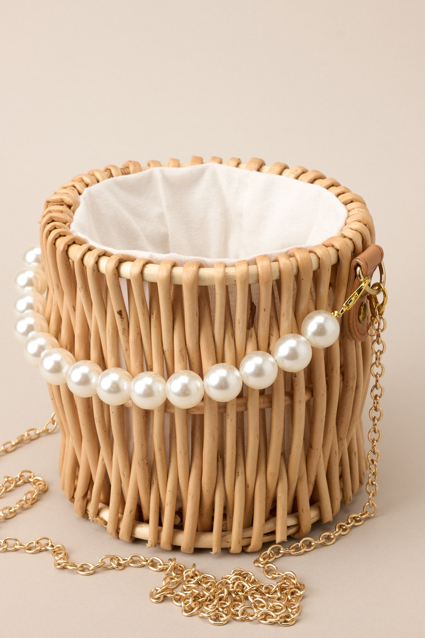 Close-in crop showing faux pearl strap attached to the gold hardware on handbag.