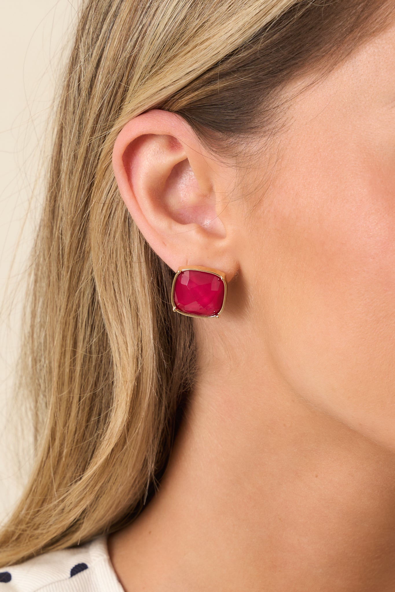 Close-in crop highlighting the deep red gemstone and smooth gold-tone setting.