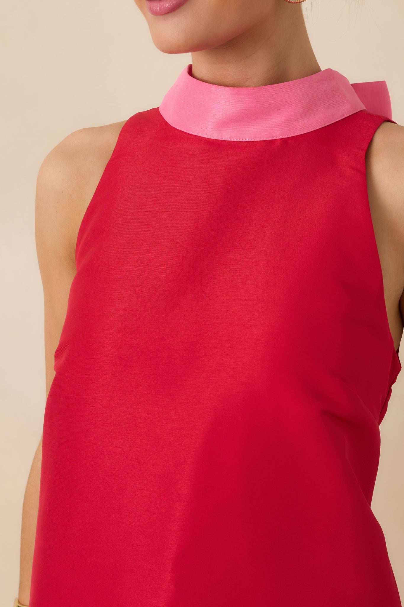 Close-up of the woven fabric texture, contrast pink trim, and neat stitching on the red mini dress.