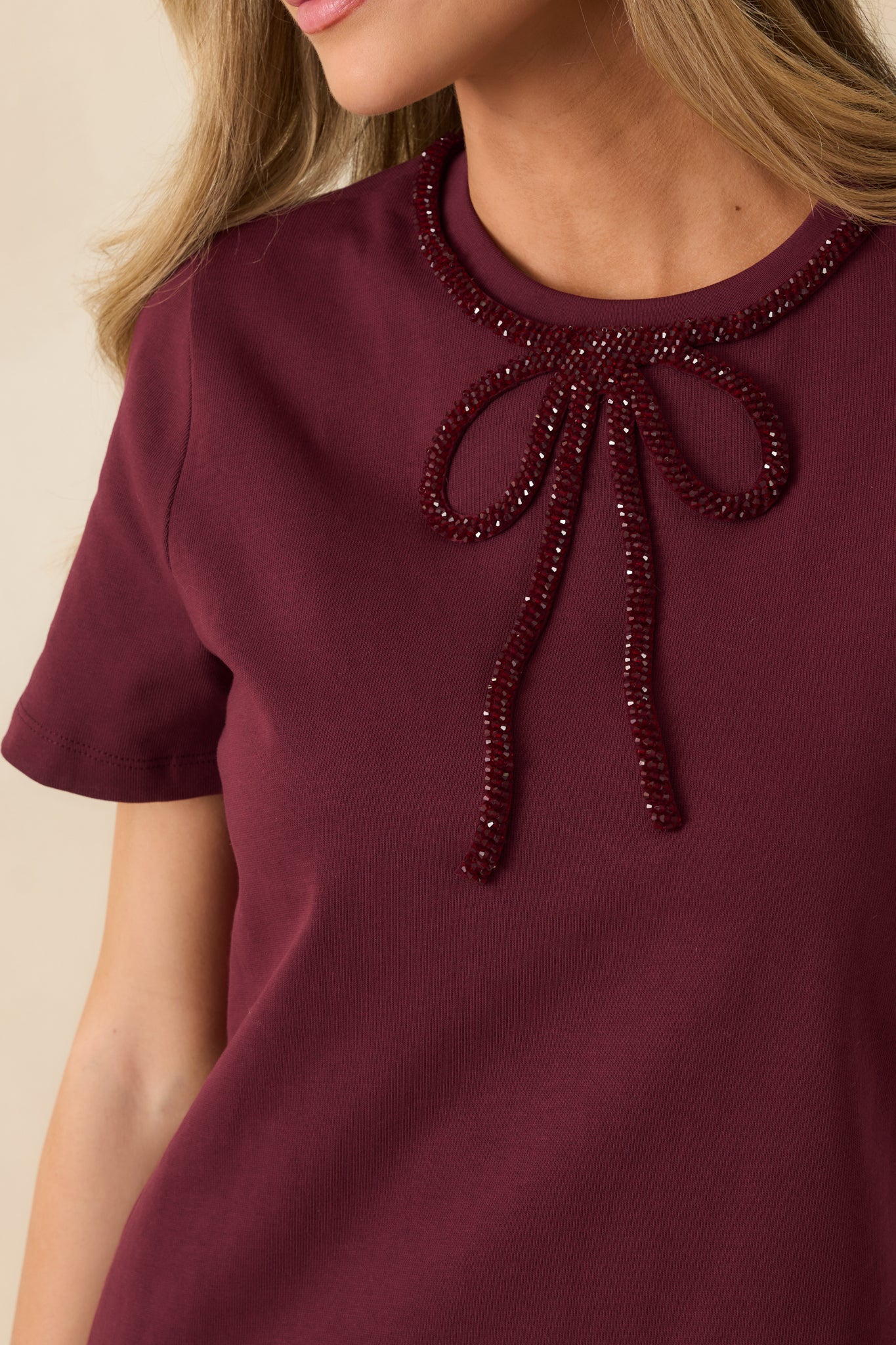 Close-up showing beaded bow at crew neckline and cotton knit texture.