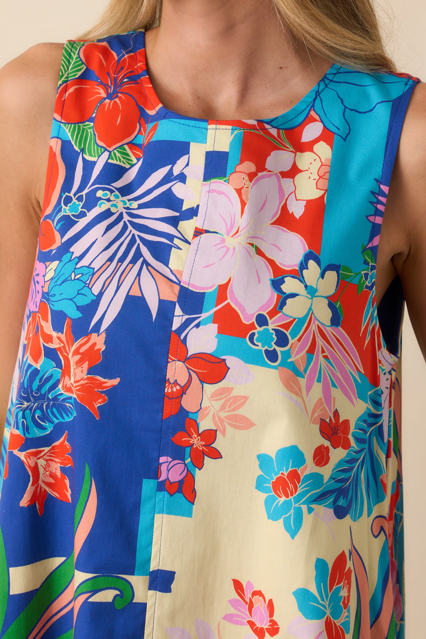 Close-up of the floral print and fabric texture on the blue mini dress, highlighting the colorful tropical design.