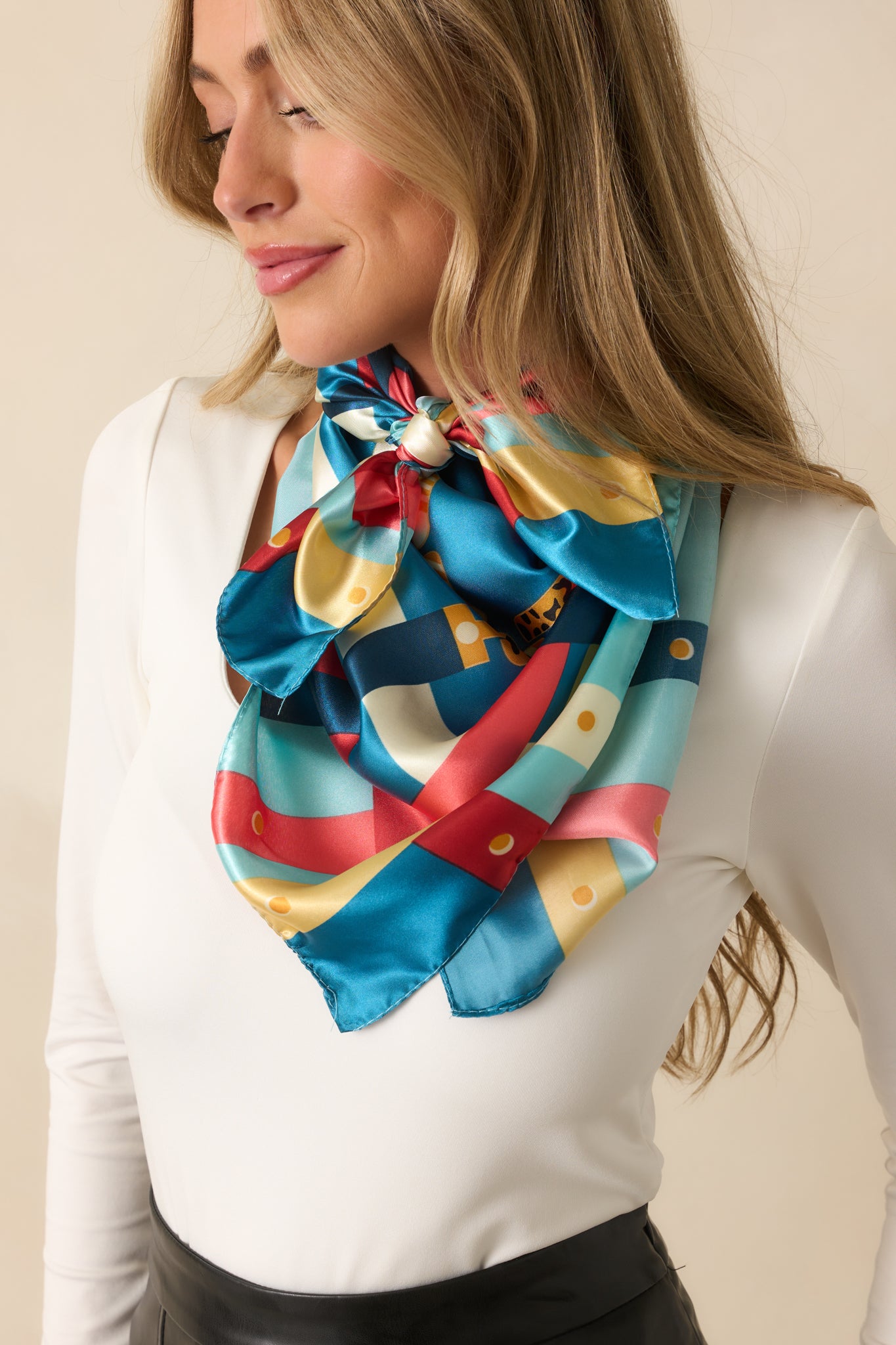 A closer look at the scarf’s blue satin material, where the multi-color chain print and bright accent hues stand out.