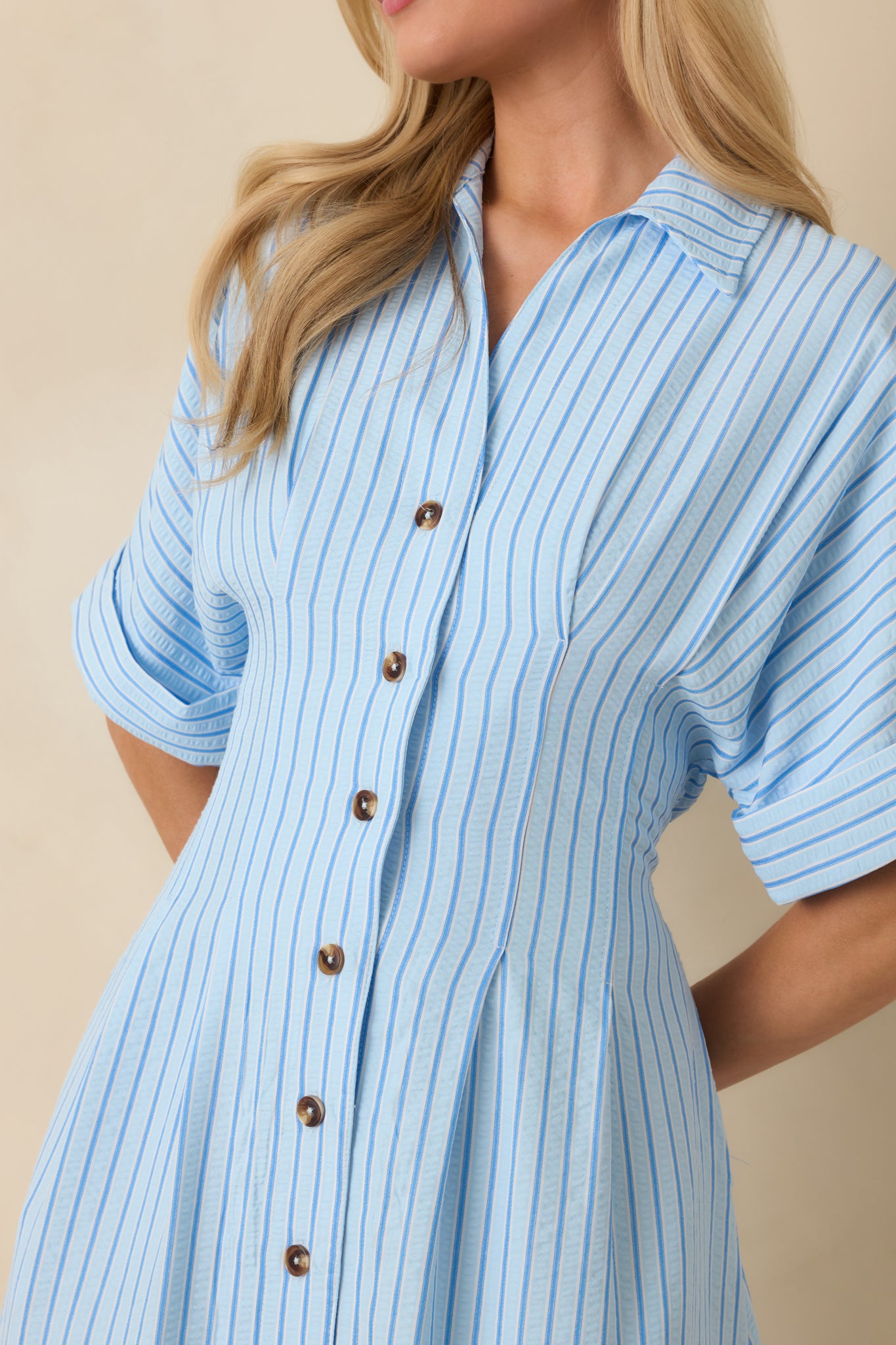 Close-up of the blue striped fabric detailing the collar, buttons, and subtle texture of the lightweight shirt dress.