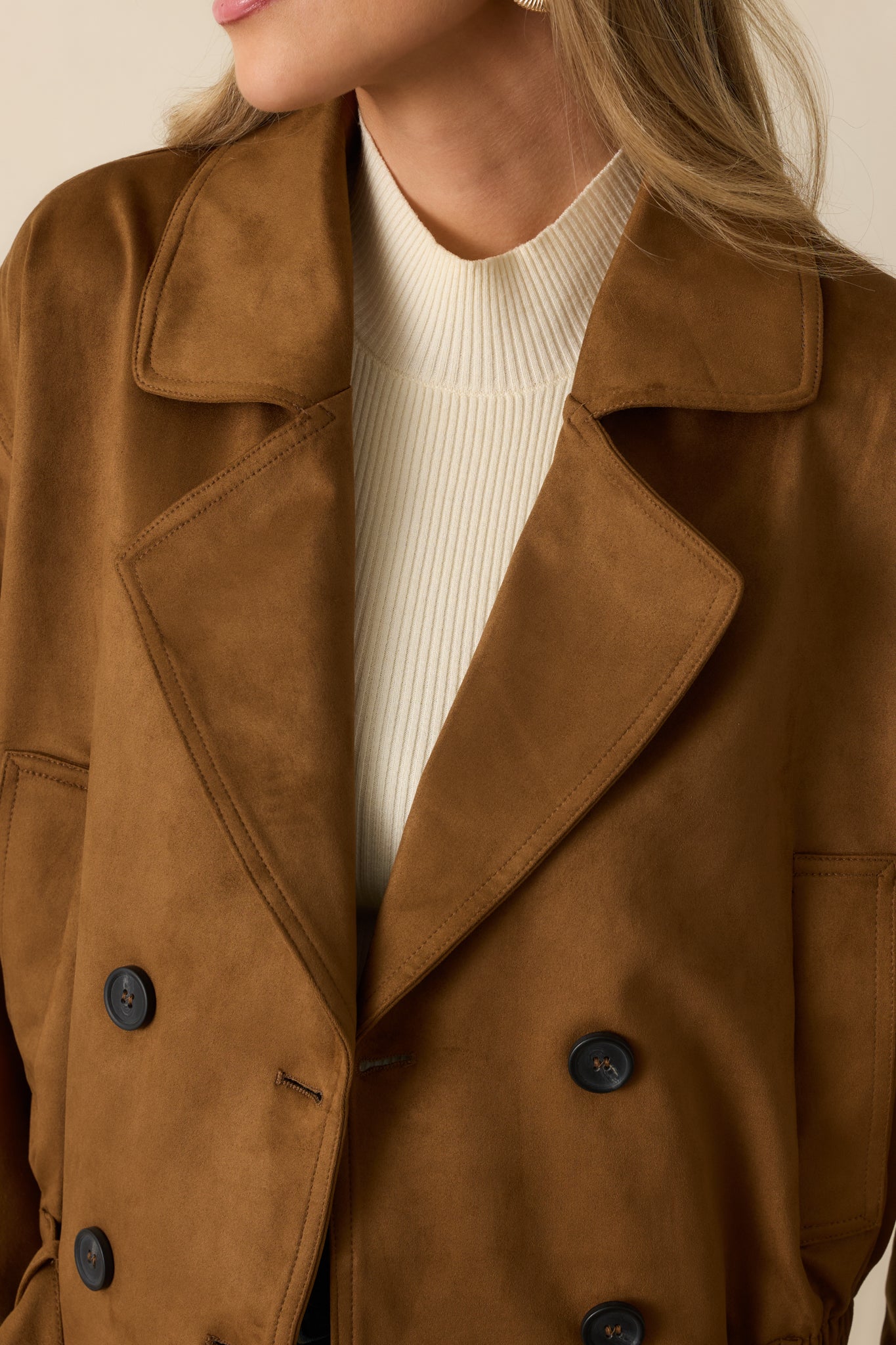 Detailed close-up of the camel faux suede fabric, button closures, and belt of the cropped trench coat.