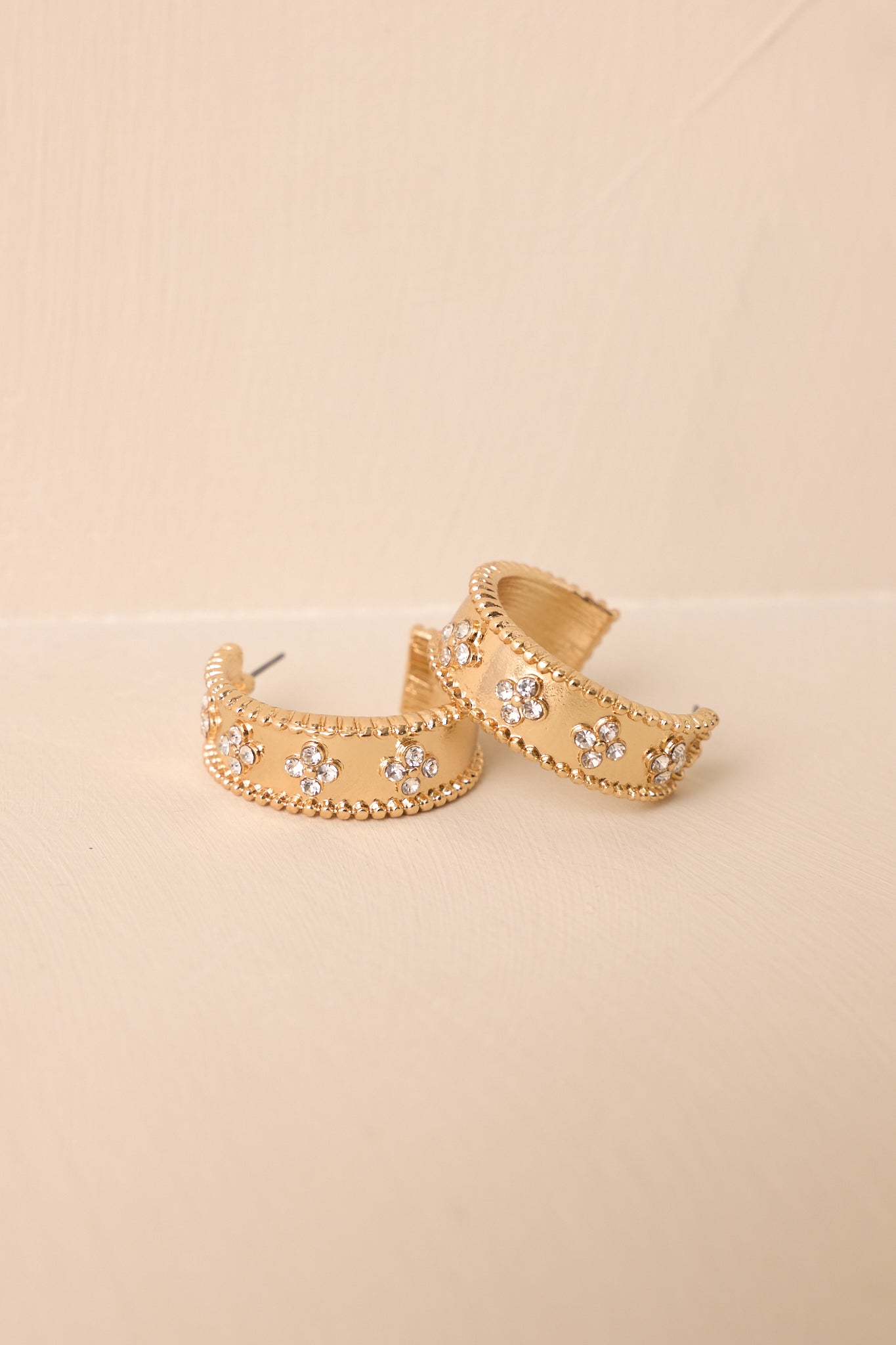 Detailed close-up capturing the brushed gold finish, beaded edge detail, and sparkling floral crystal embellishments.