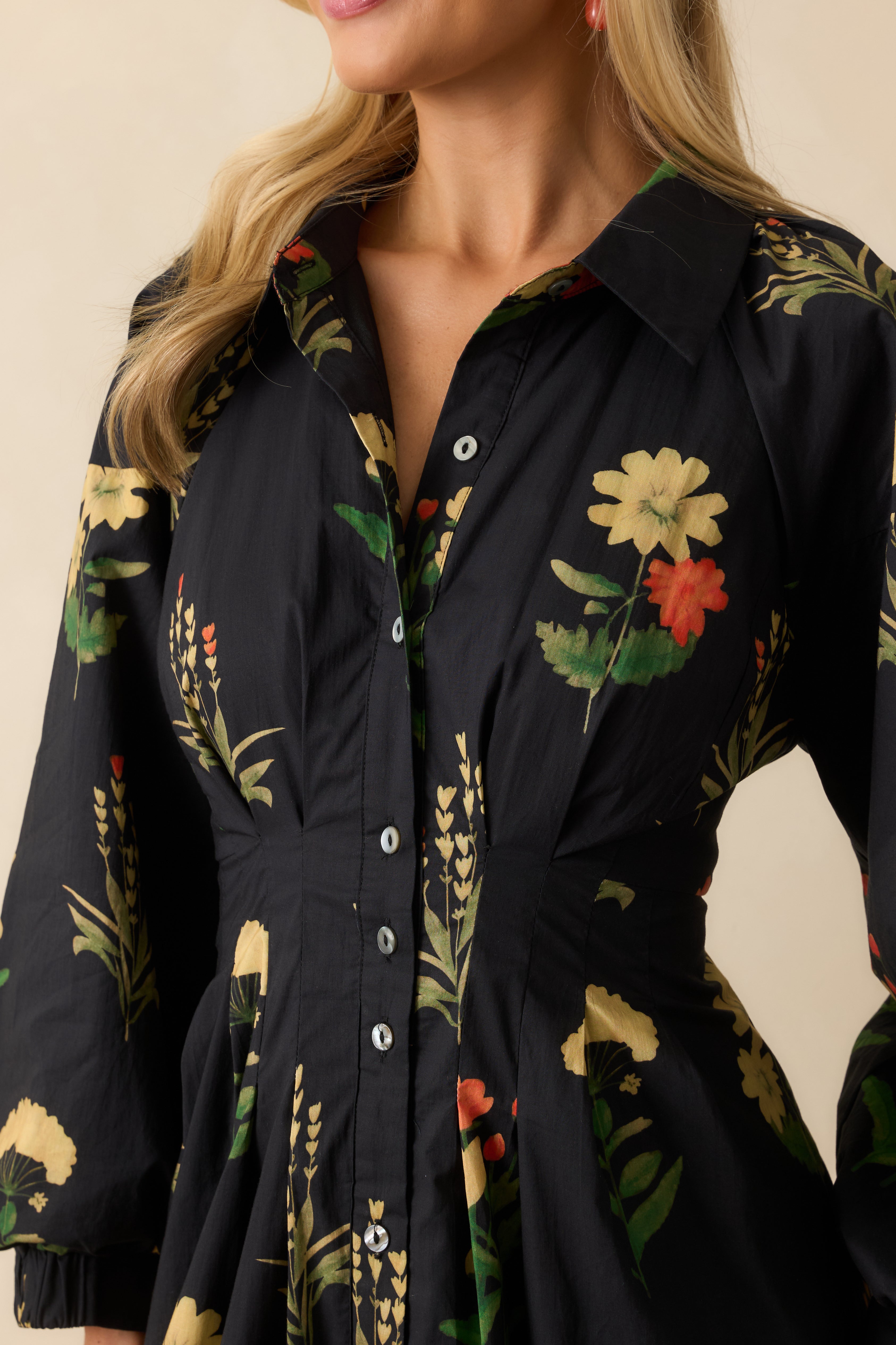 Close-up of the collared neckline, button-front closure, and pleated waist with floral print.