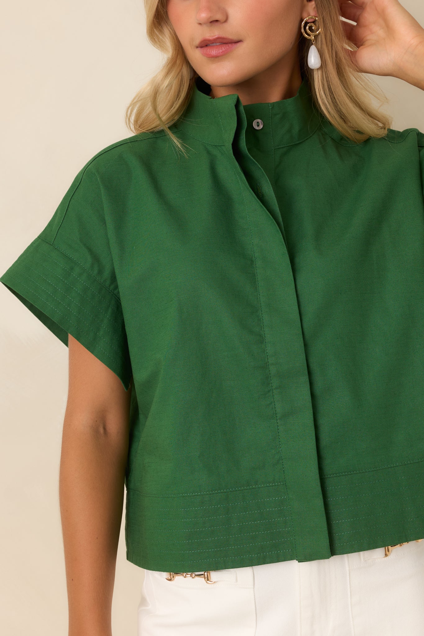 Close-up of the cotton linen top highlighting the mock neckline, concealed buttons, stitch detailing, and woven texture.