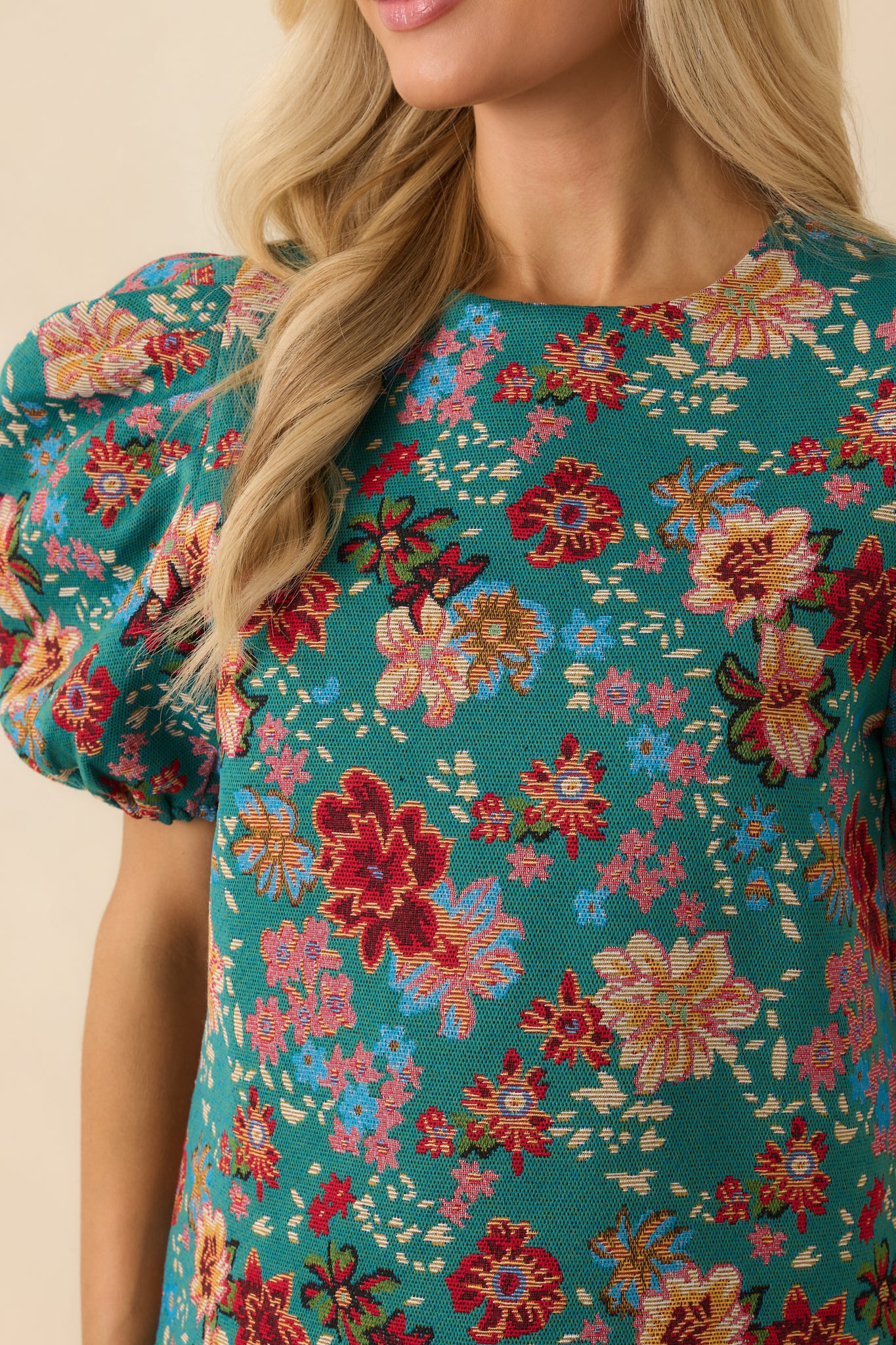 Close-up detail of the teal-green top emphasizing the floral pattern, woven texture, and puff sleeve gathering.