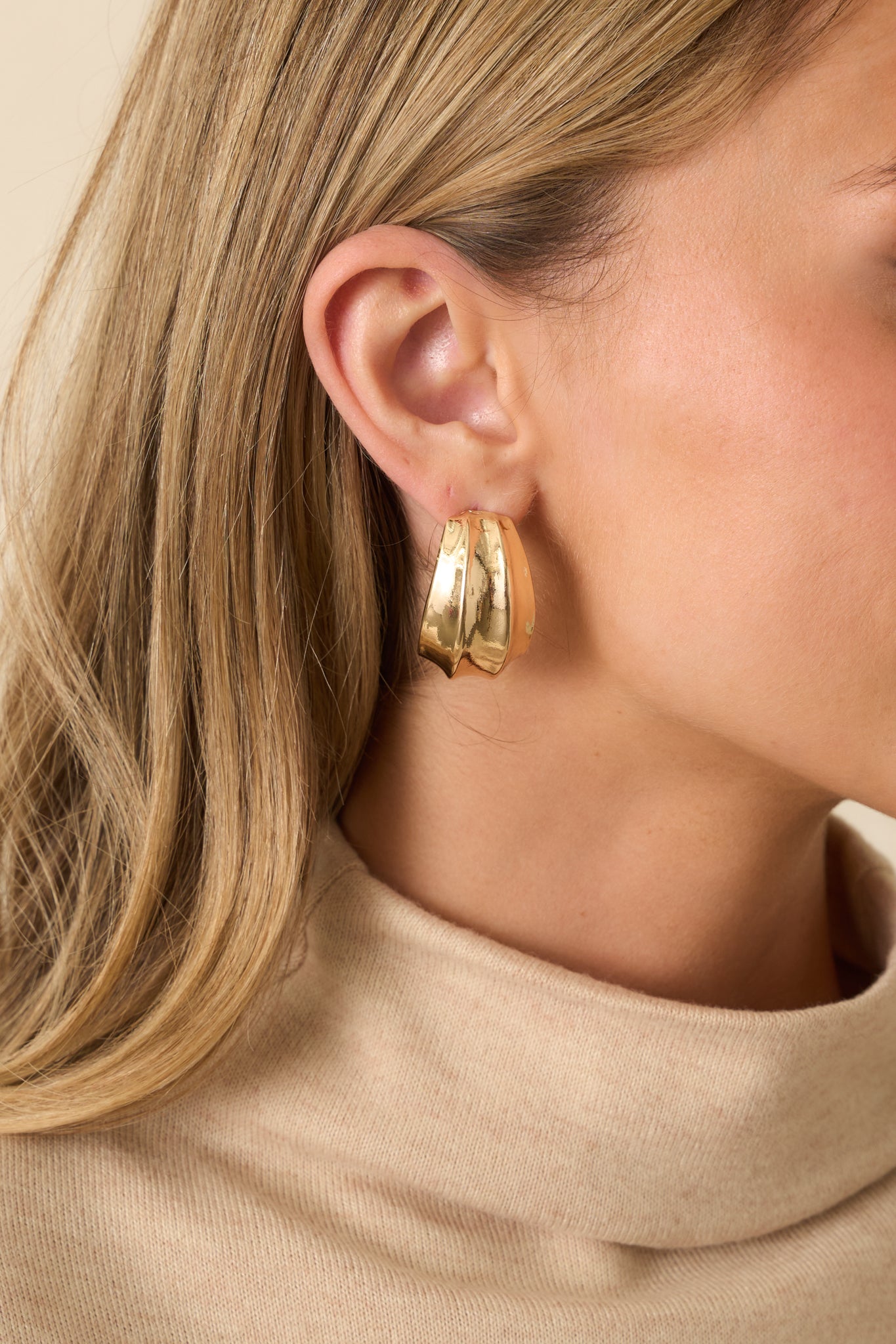 Close-up detail of the earrings, highlighting the textured surface and smooth polished finish.