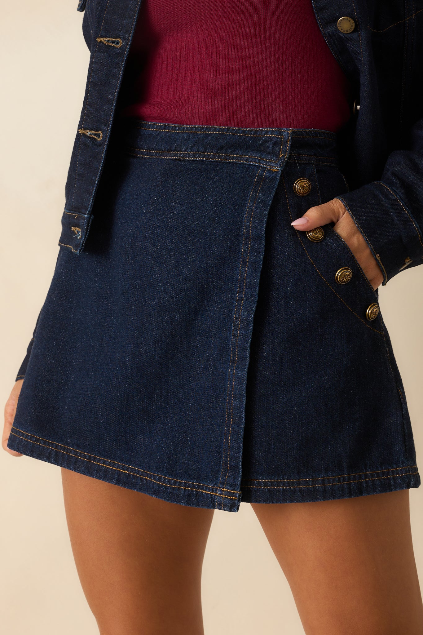 Close-up of the embossed gold buttons, tan topstitching, and fabric texture on the skort.