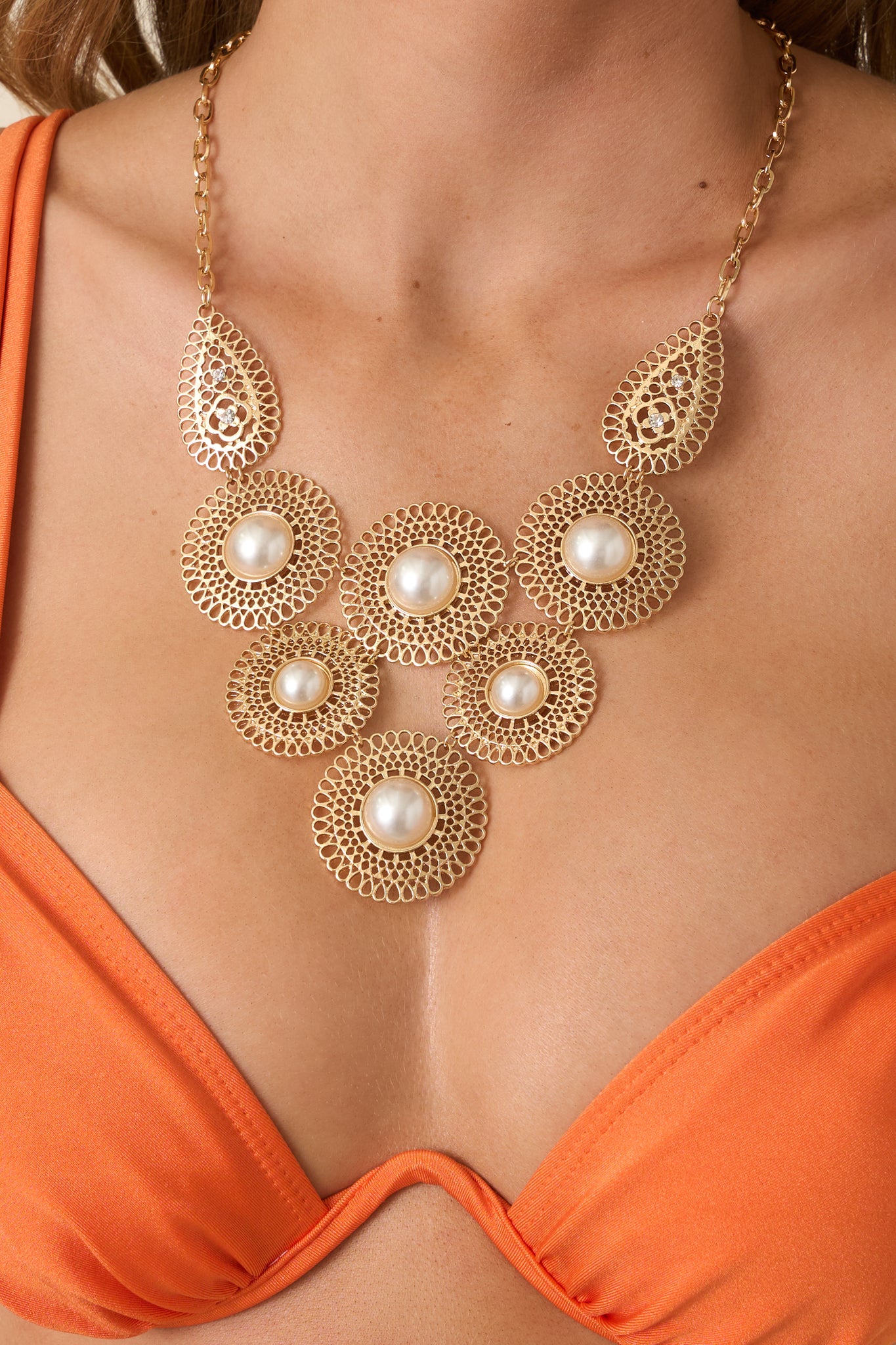 Close-up detail of the necklace highlighting the intricate filigree discs, pearl centers, and rhinestone teardrop connectors.