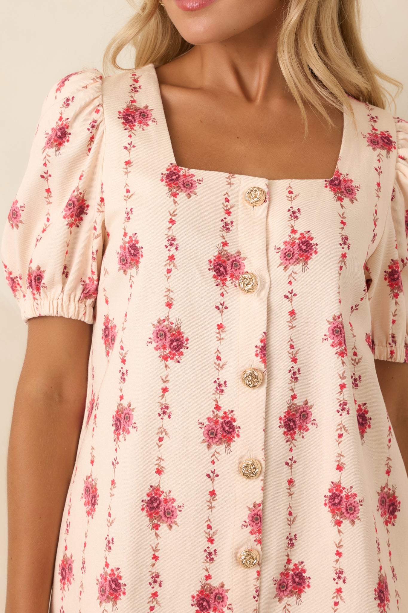 Close-up of the floral mini dress highlighting rose bouquet embroidery, square neckline, puff sleeve detail, and gold buttons.