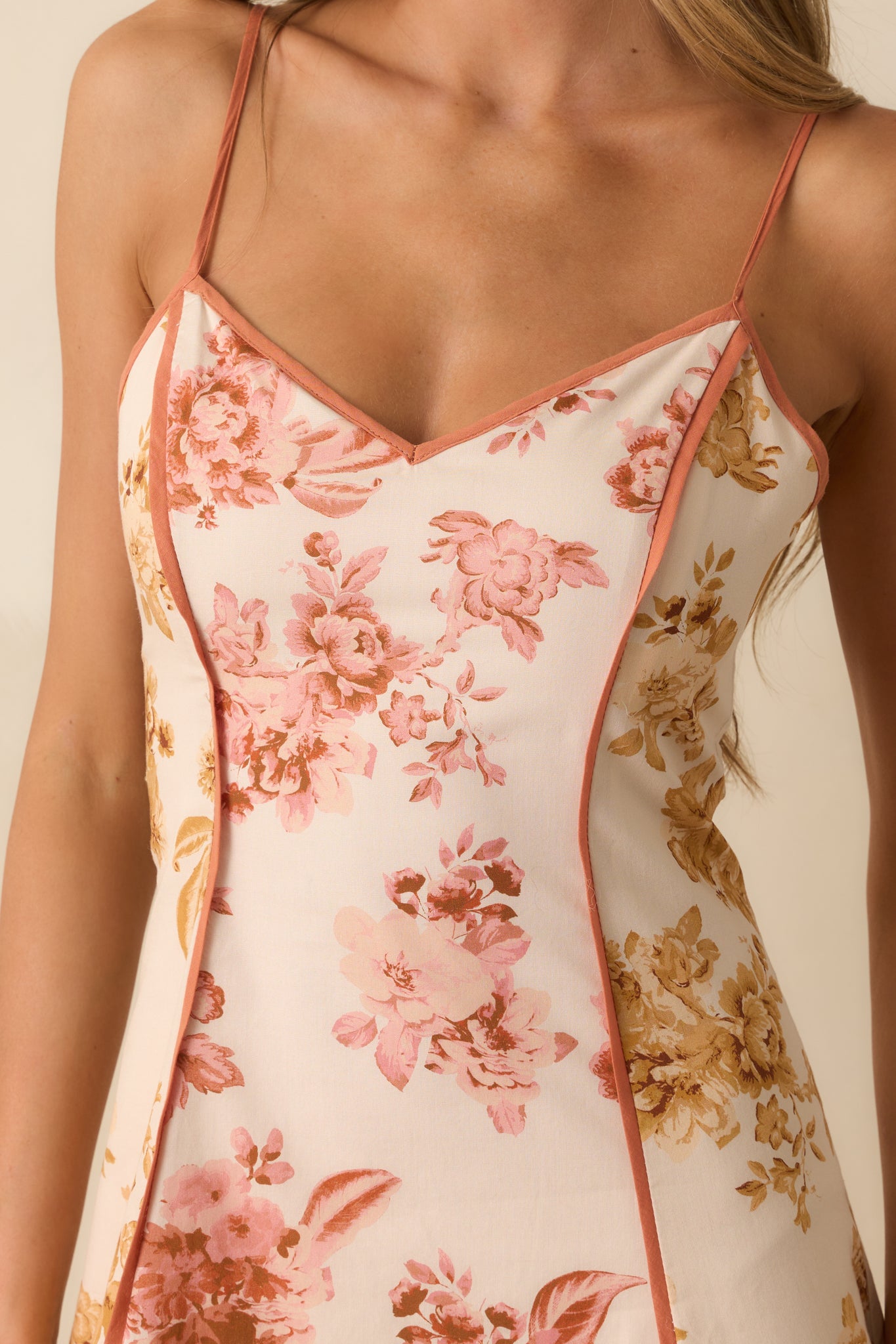 A detailed close-up of the floral print fabric, clay trim, and V-neckline stitching.