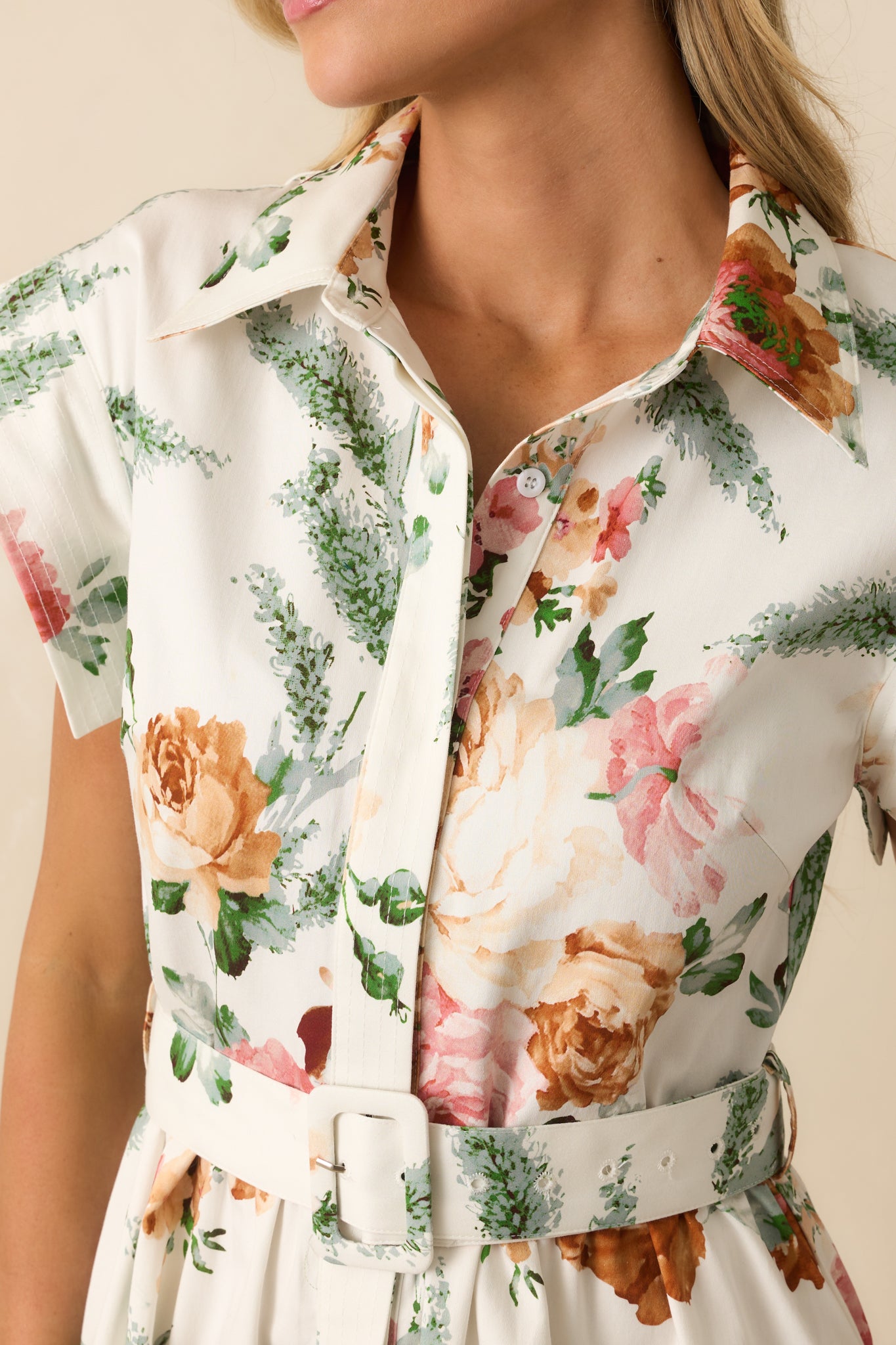 A detailed close-up of the floral print fabric, topstitching, and button closure.