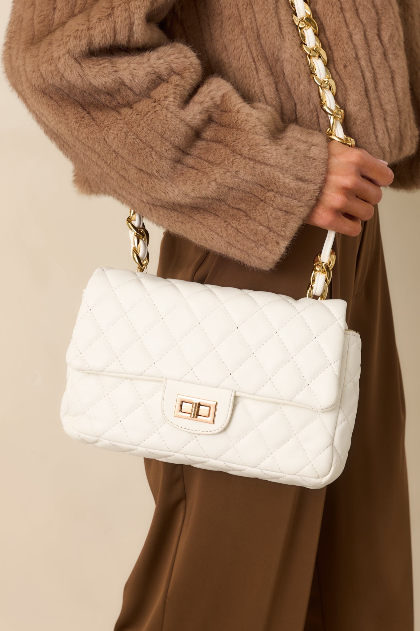 Detailed close-up of the white bag focusing on the quilted texture, turn-lock closure, and gold hardware.