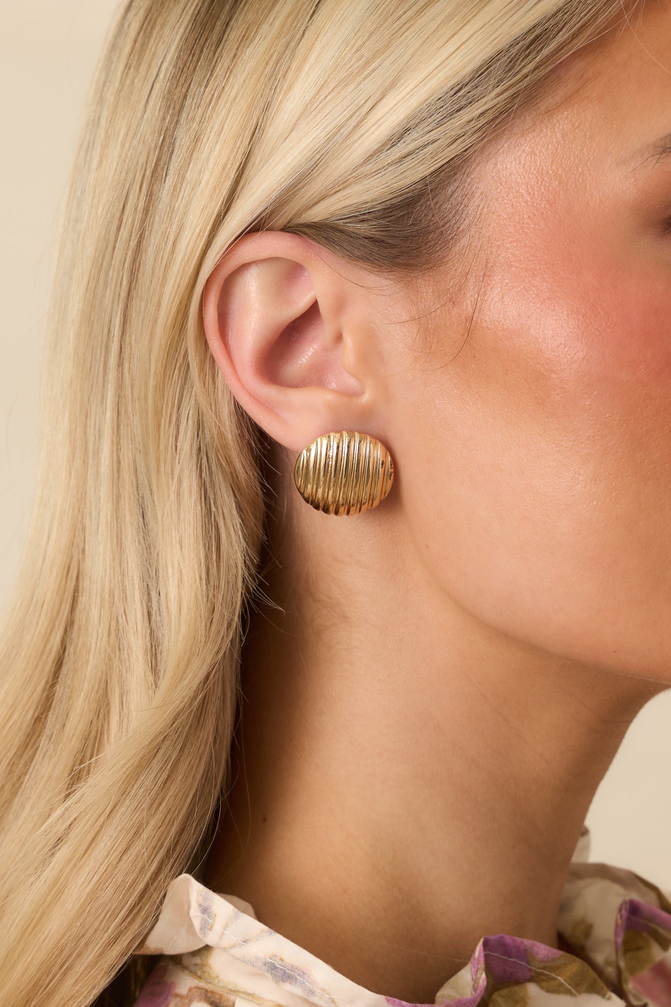 Close-up of gold circular earrings highlighting the ribbed texture.