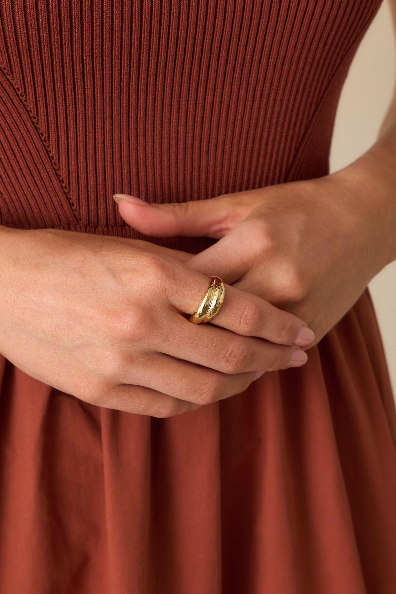 Close-up of a gold ring showing its slip-on band and hammered finish highlighting the overlapping crossover pattern