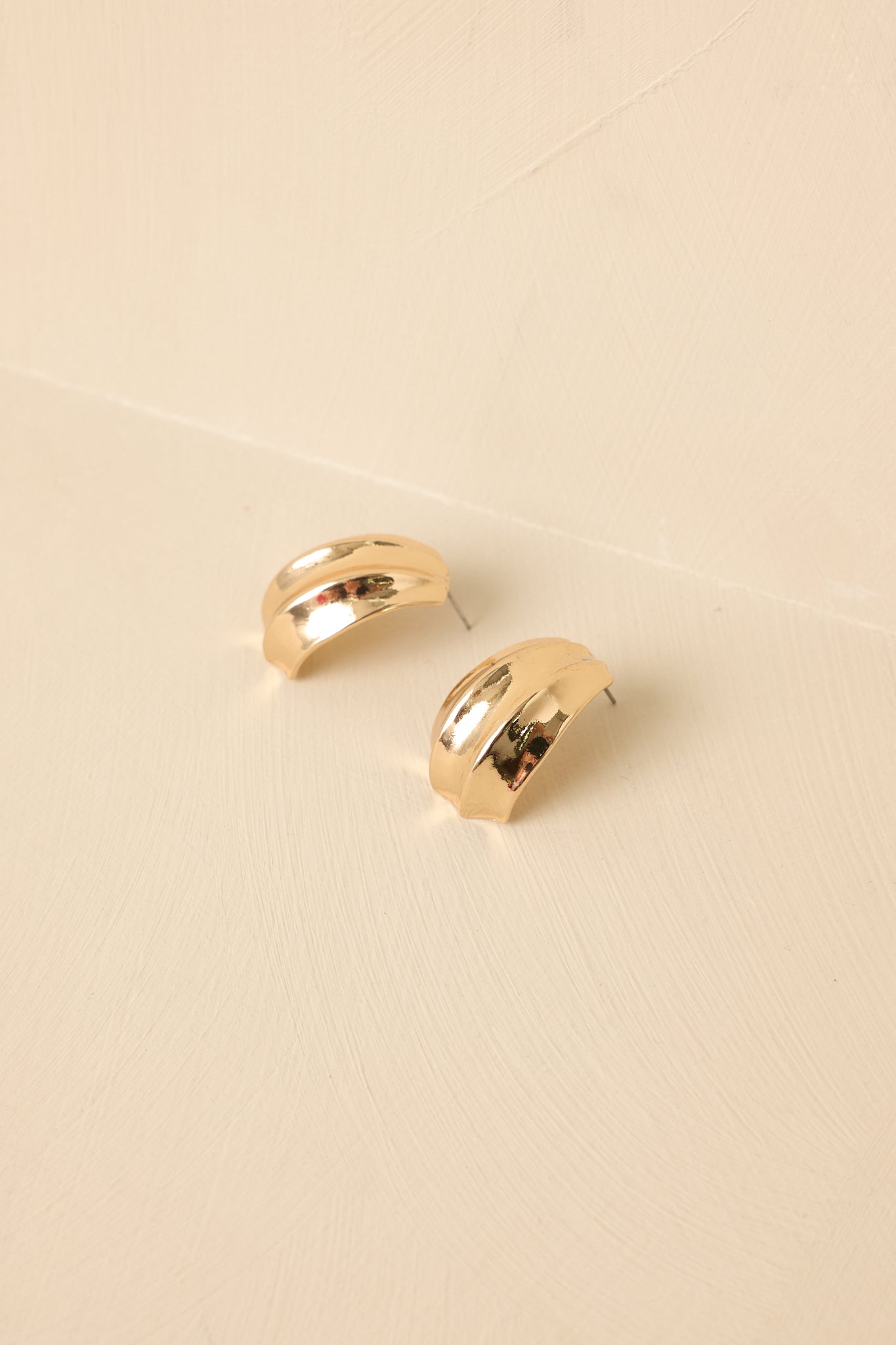 Detailed close-up of the gold stud earrings focusing on the slightly fanned texture, polished finish, and secure posts.