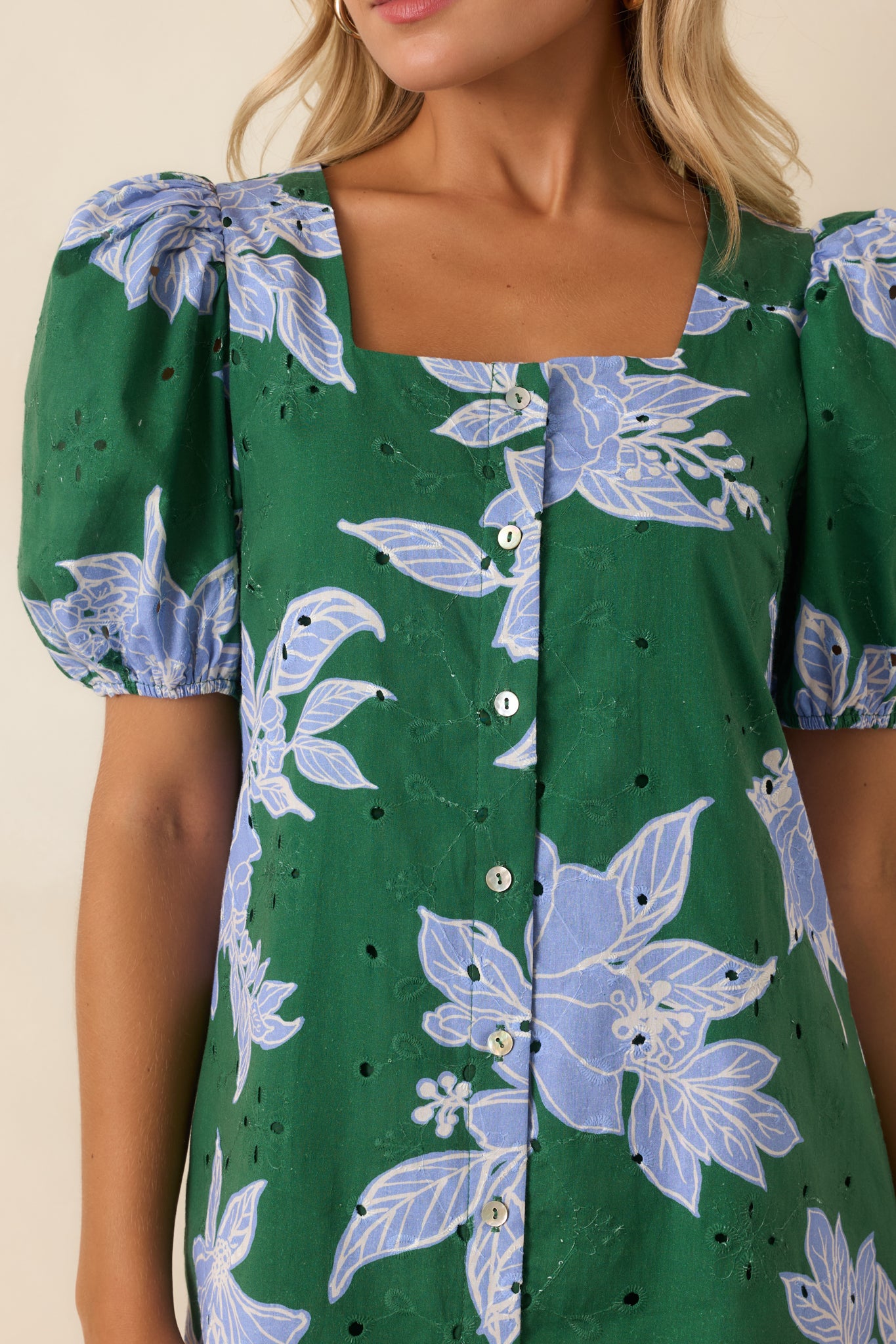 Close-up of the green eyelet dress highlighting the blue floral print, embroidered texture, button front, and neckline detail.