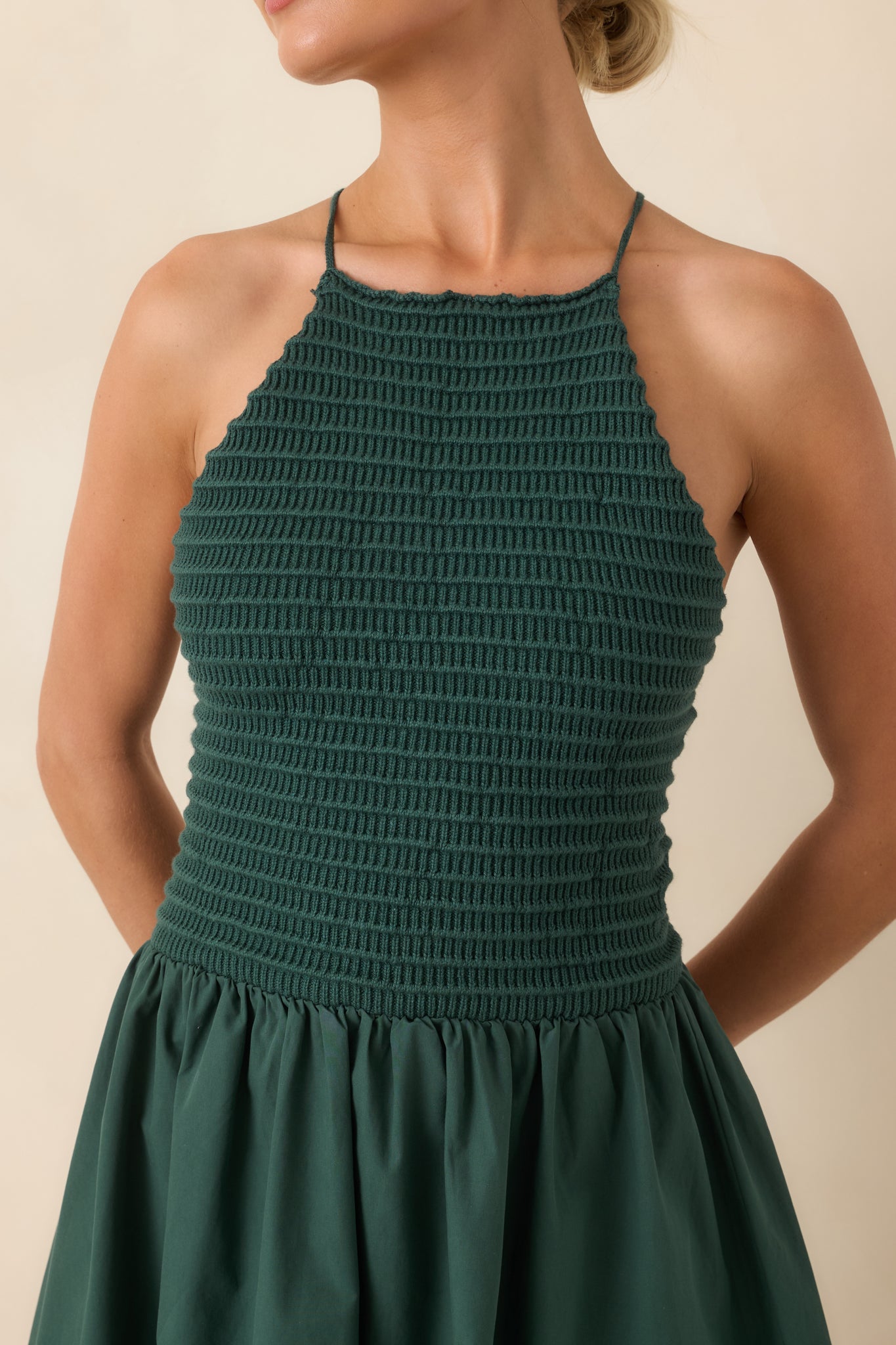 Close-up of the green midi dress highlighting the fitted knit bodice, high halter neckline, soft cotton fabric, and refined construction details.
