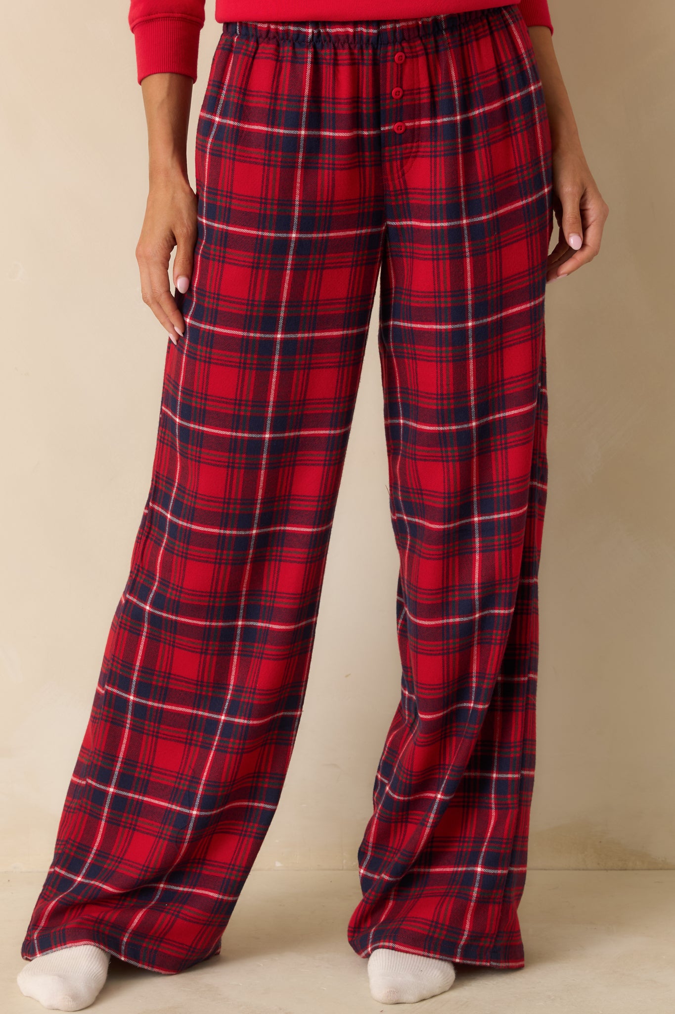 Close-up of the high-rise waistband and side seam pocket on red plaid pajama pants, showing lightweight flannel texture.