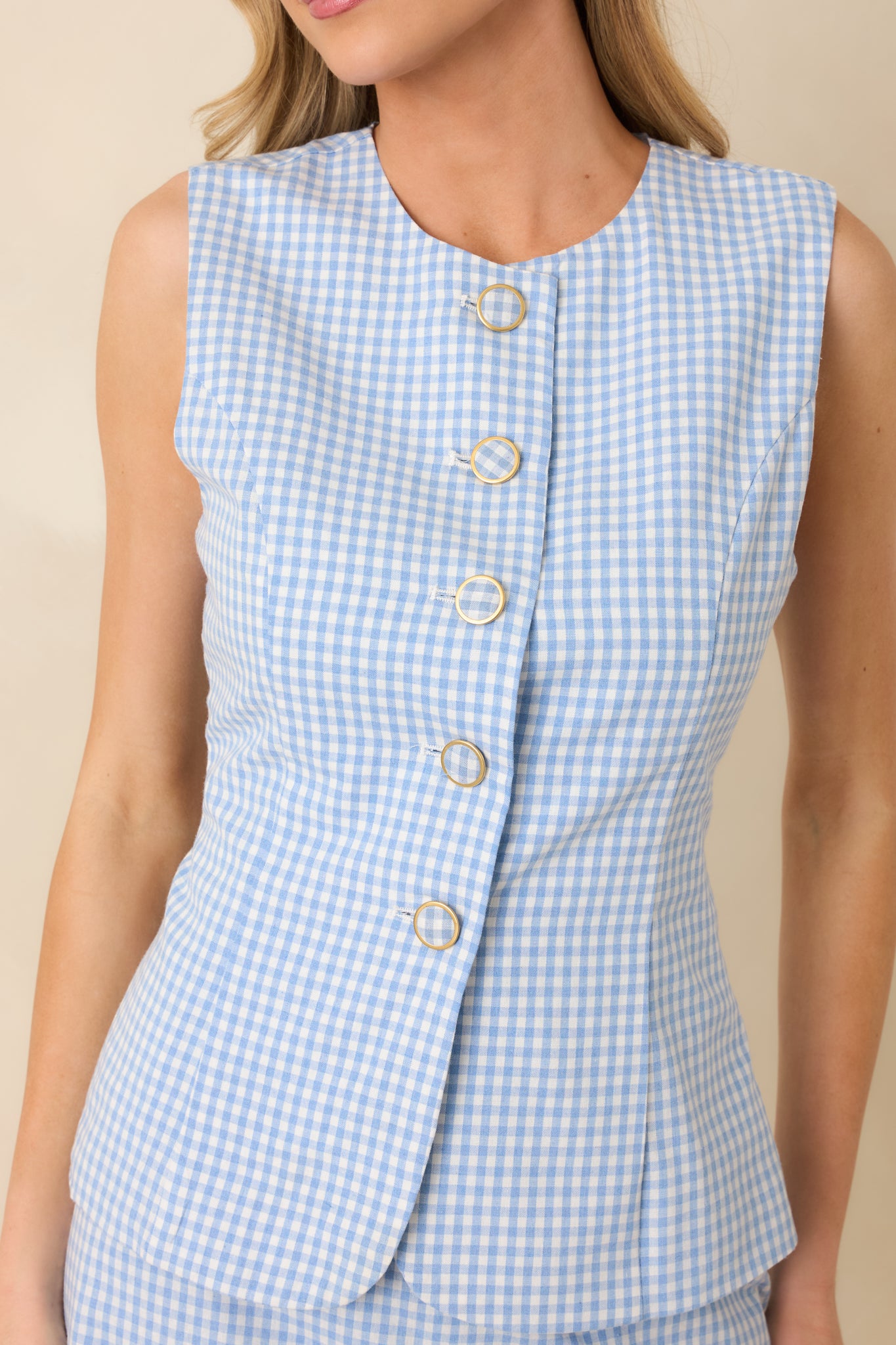 Close-up of blue gingham fabric highlighting button closure and finely stitched seams.