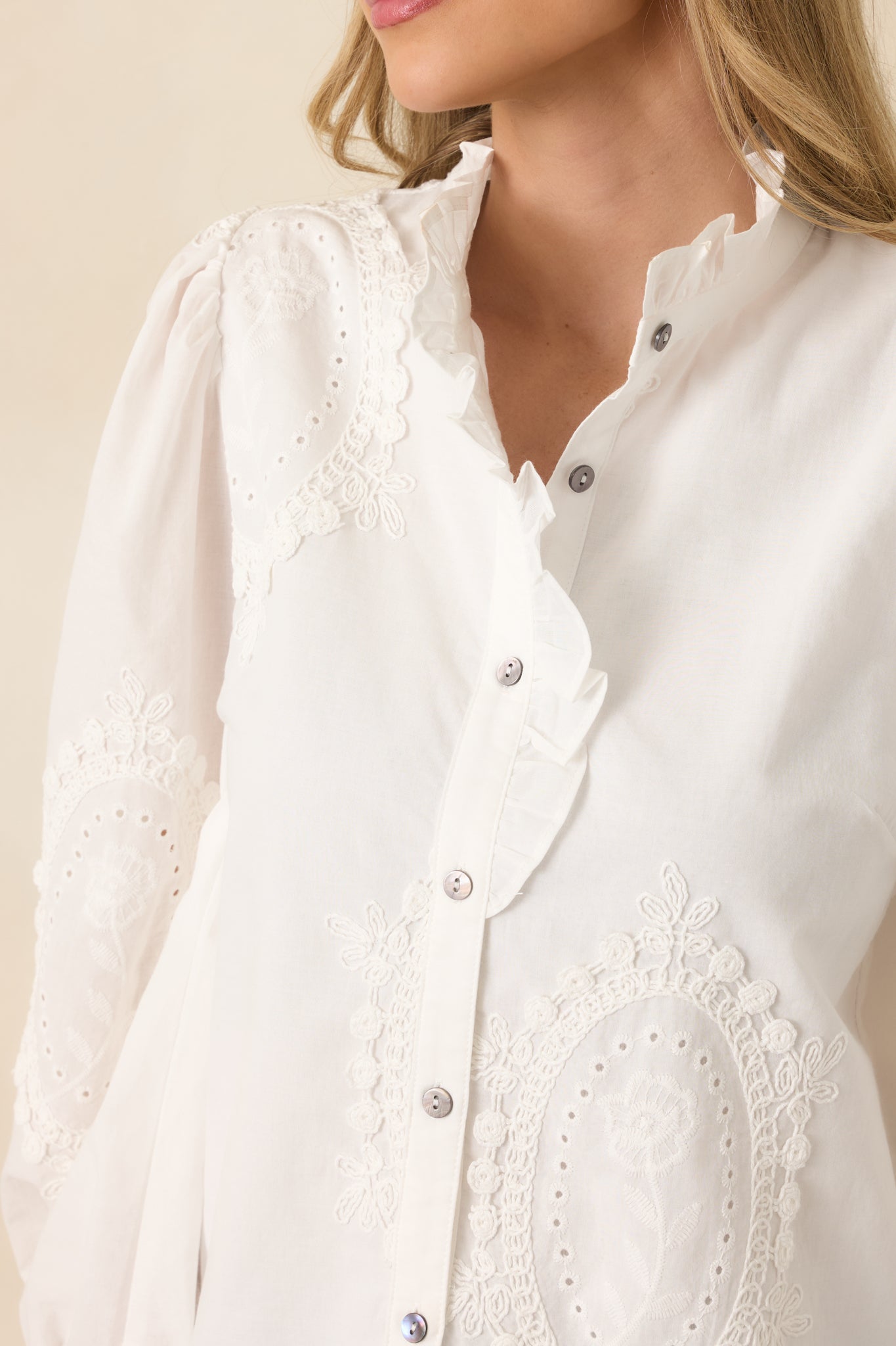 Close-up of the white blouse highlighting the intricate eyelet appliqué and lightweight cotton weave.