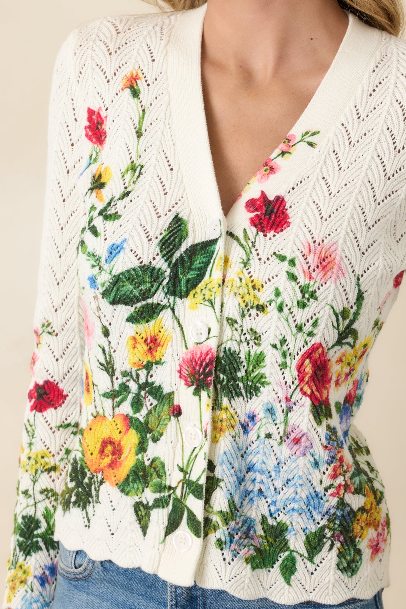Close-up detail of the ivory cardigan highlighting the floral print, scalloped hem, and textured pointelle knit.