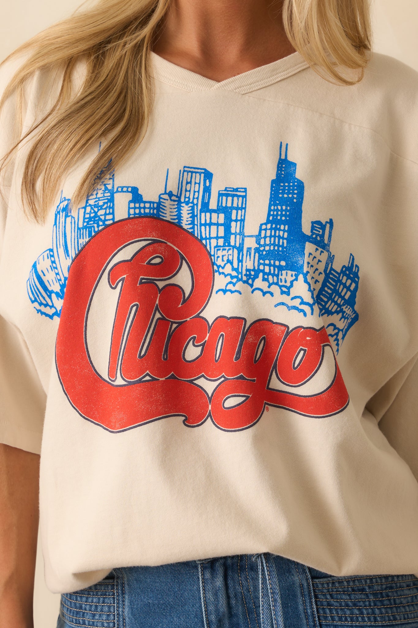 Detailed close-up of ivory oversized T-shirt’s v-stitch neckline, textured fabric, and vivid layered graphic print.