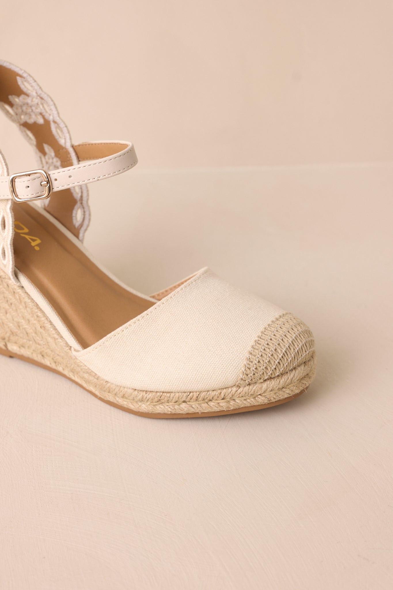 A zoomed-in image focusing on the knit tip of the toe piece and the texture of the woven straw wedge heel.