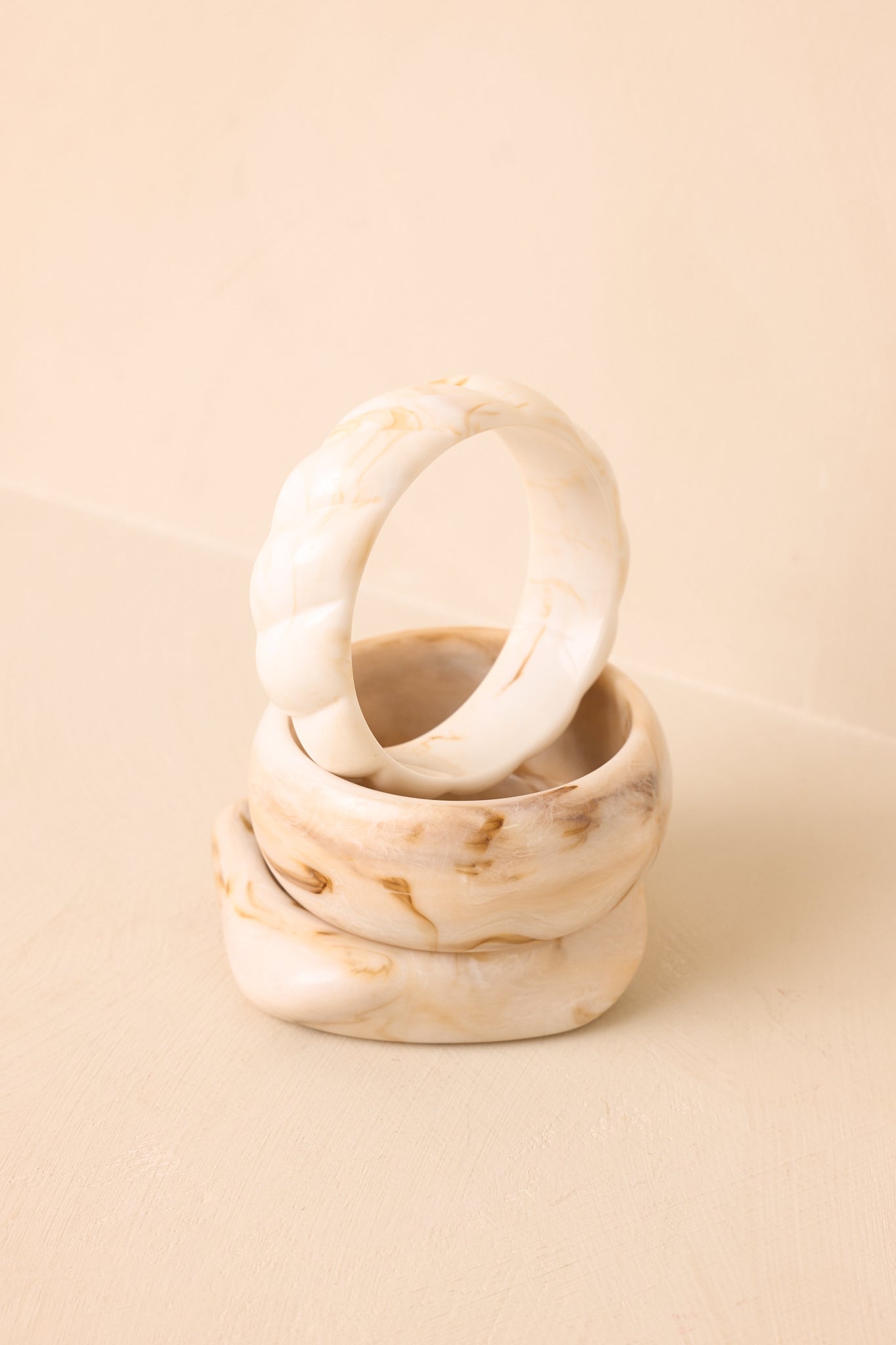 Close-up of the marbled ivory finish and sculptural shapes featured throughout the three-piece bangle set.