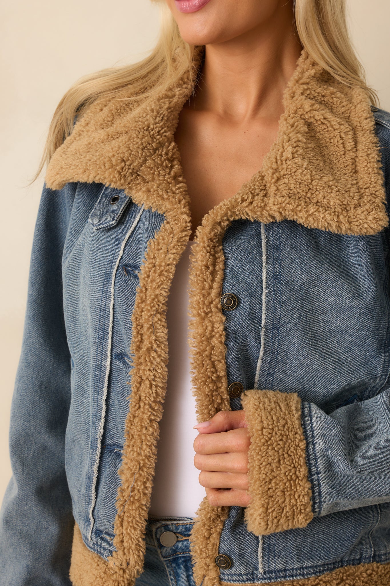 Close-up of medium wash fabric with camel sherpa collar, button closure, and pocket detailing.