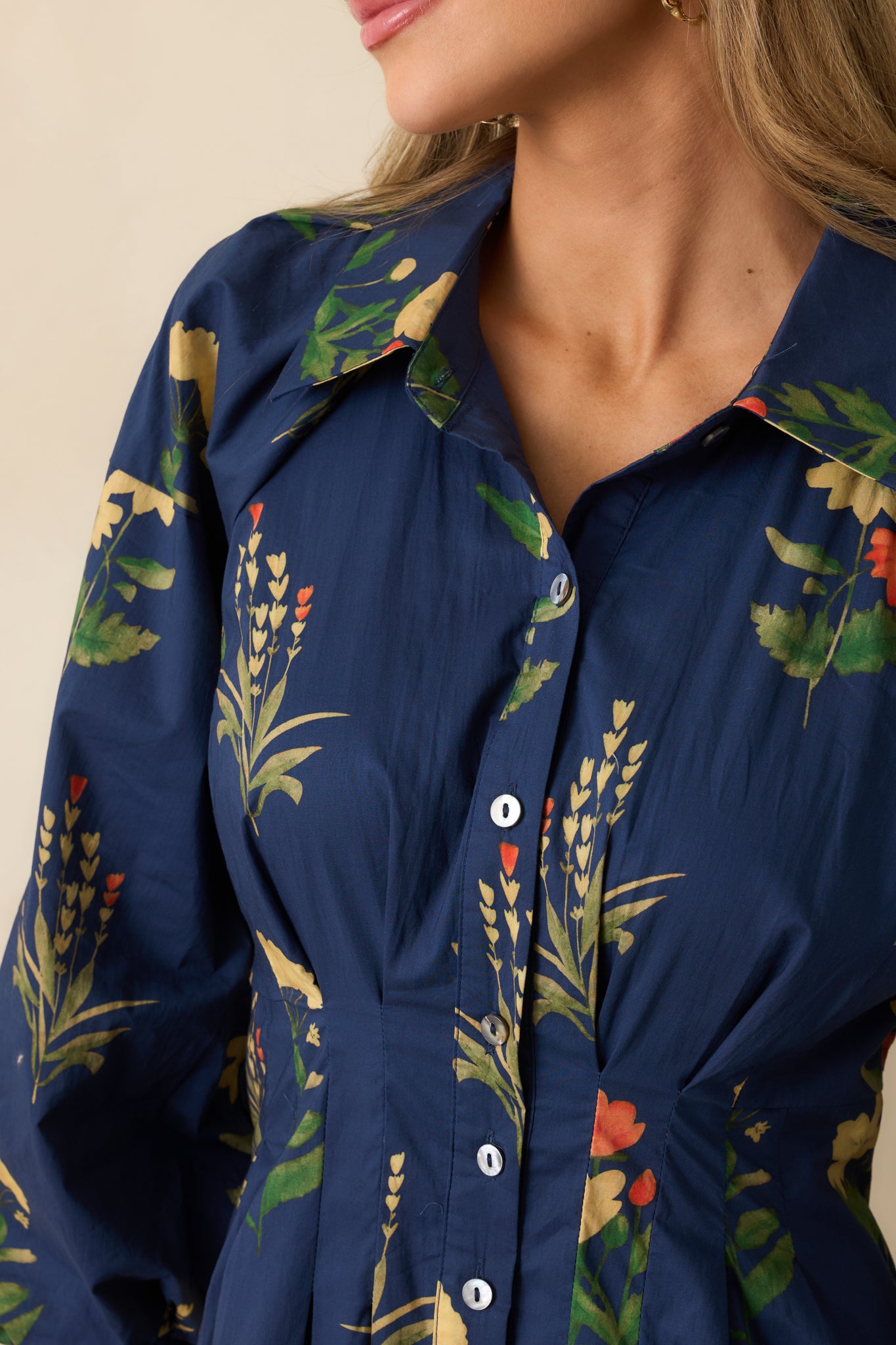 Close-up of the navy fabric displaying the floral print, pleated waist, and texture of the woven material.
