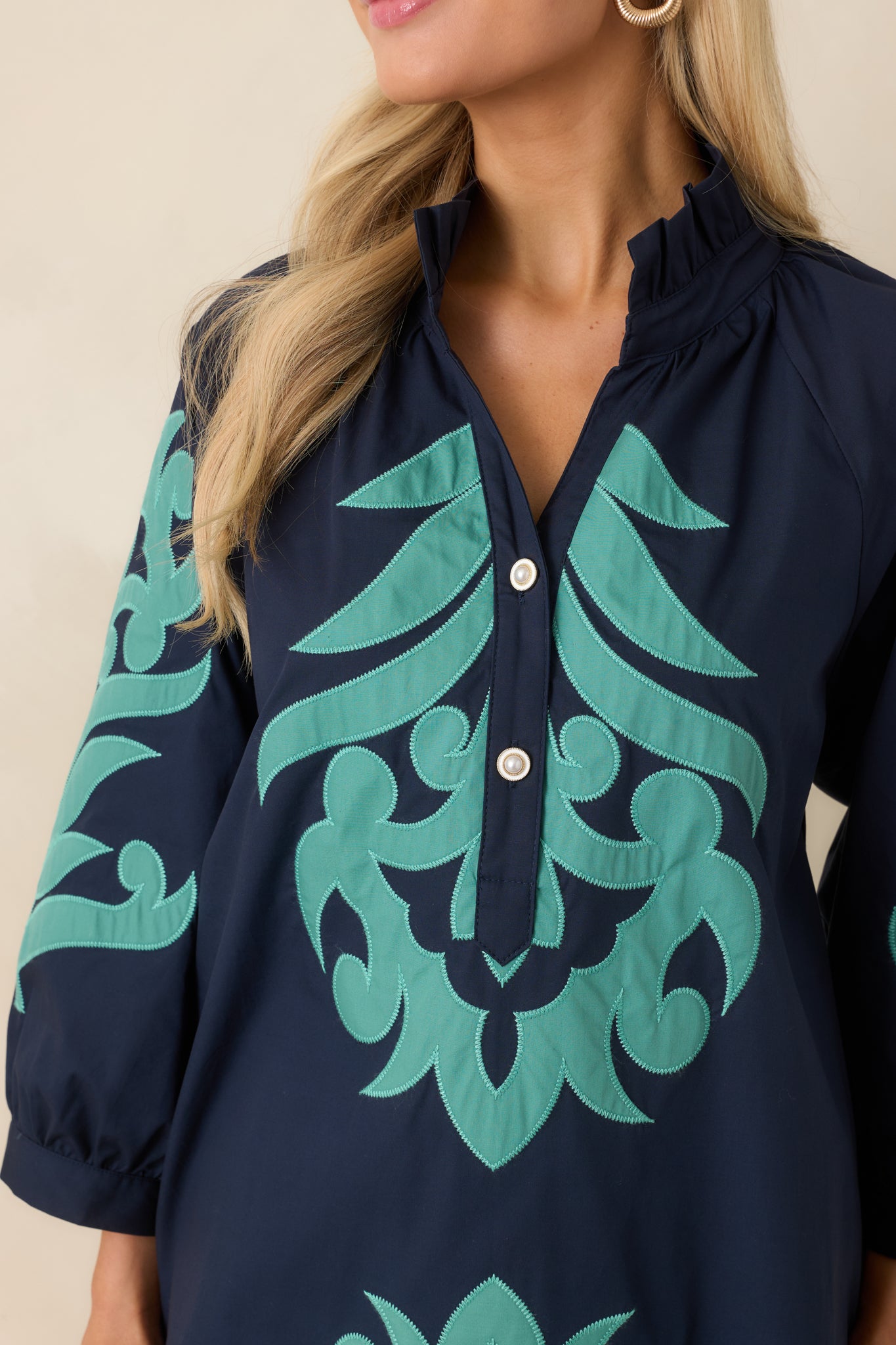 Close-up of aqua contrast trim and split neckline with button accents.