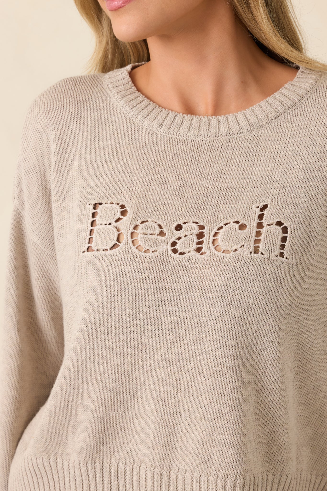 Close-up of “Beach” embroidery showing raised stitched texture on ribbed knit fabric.