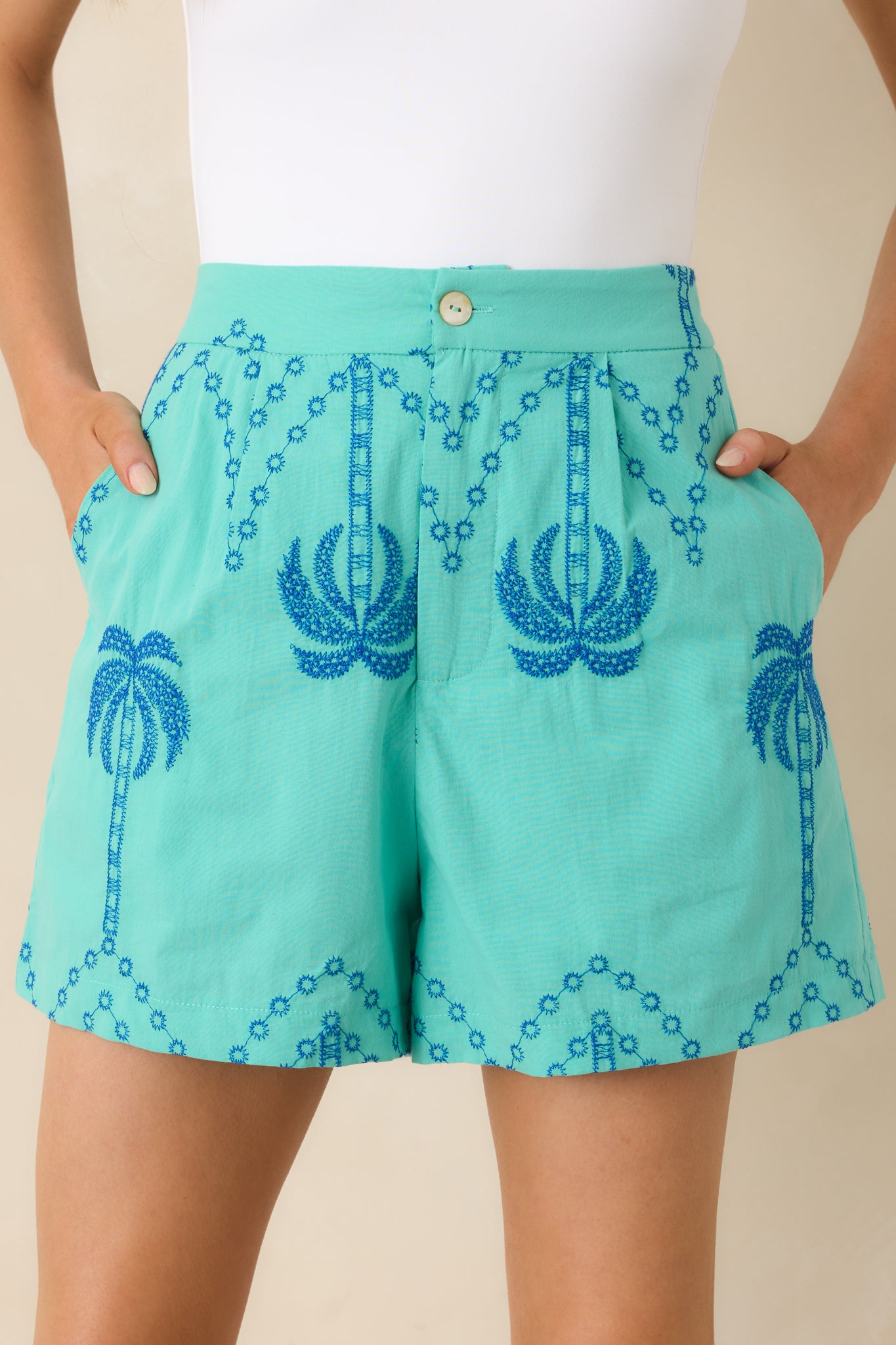 Close-up of palm tree embroidery with fine stitching on lightweight cotton fabric.