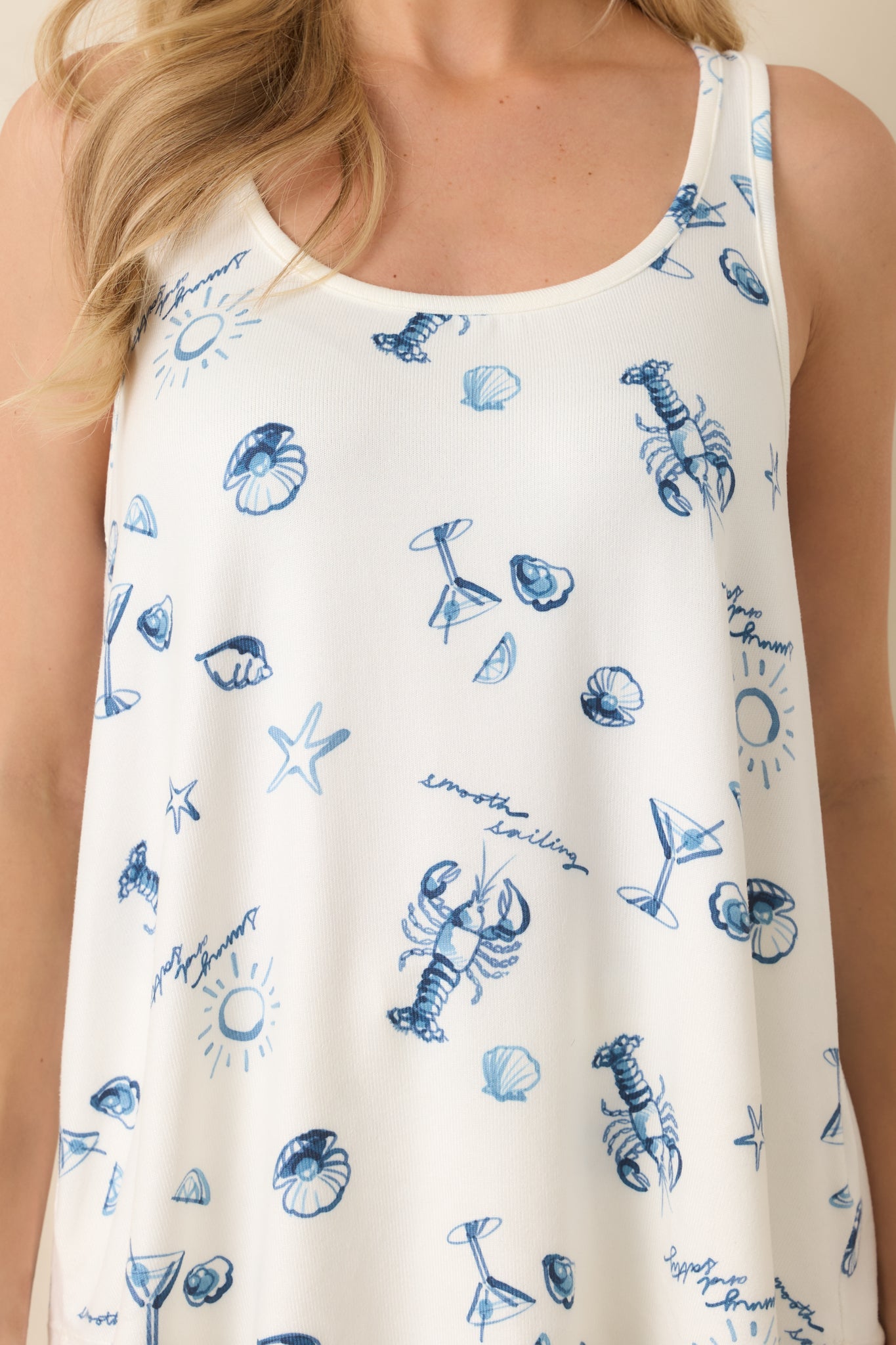 Close-up of blue seaside graphics, including lobsters, shells, and starfish on soft ivory fabric.
