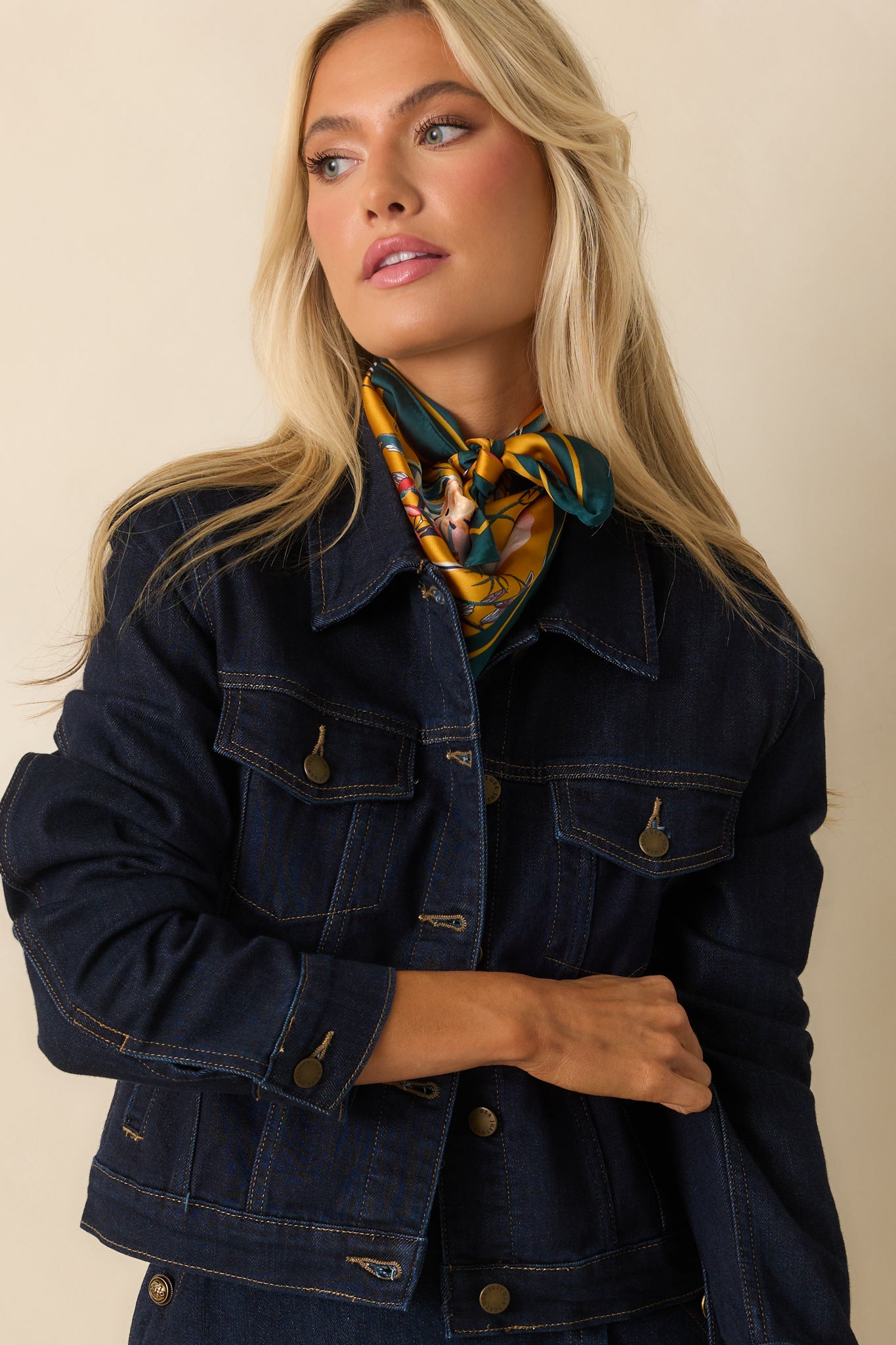 Close-up of the collared neckline and top button detail on the dark wash denim jacket.