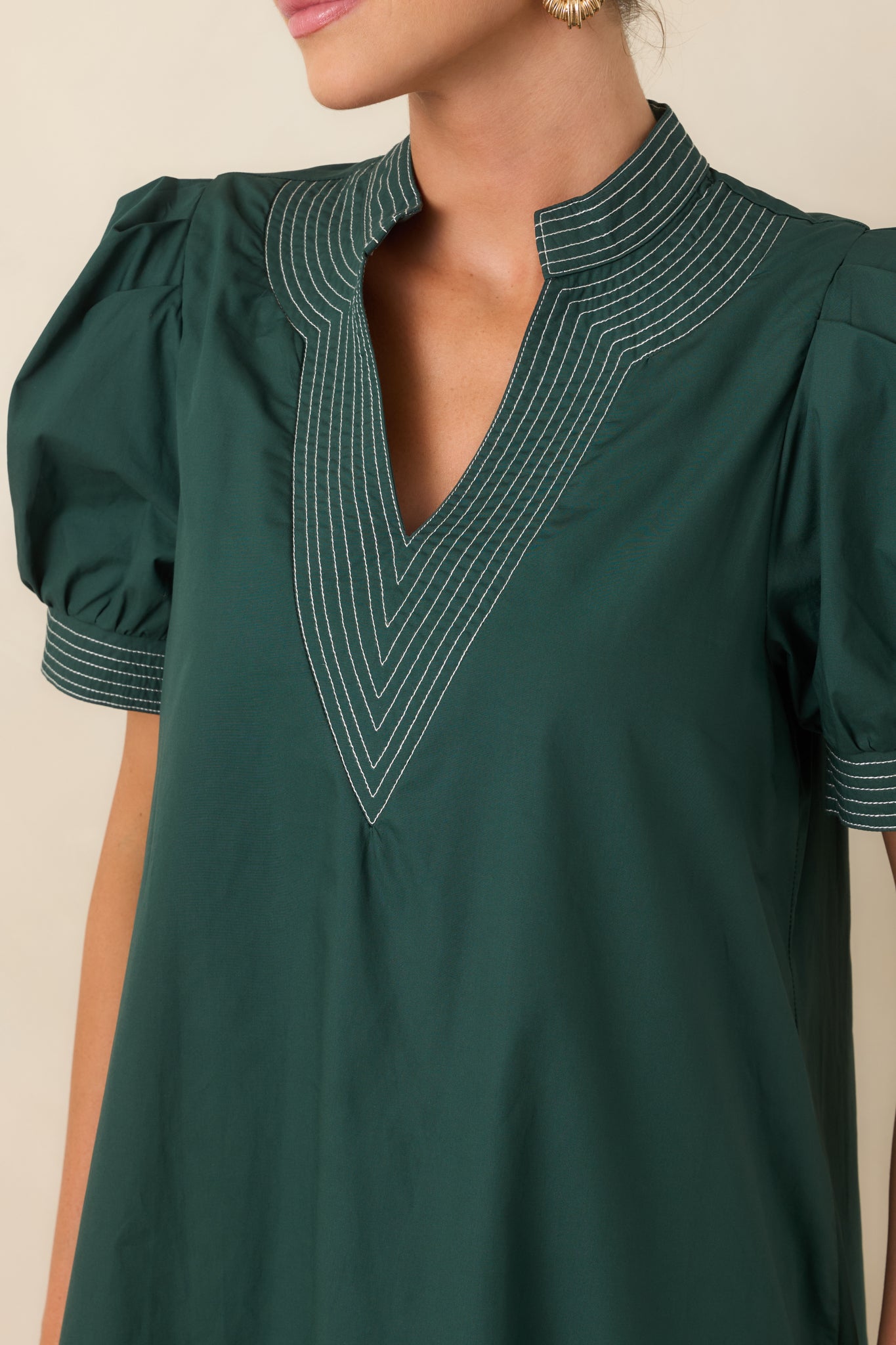 Close-up view of the layered contrast stitching, split neckline, and stitched cuff detailing on the dress.
