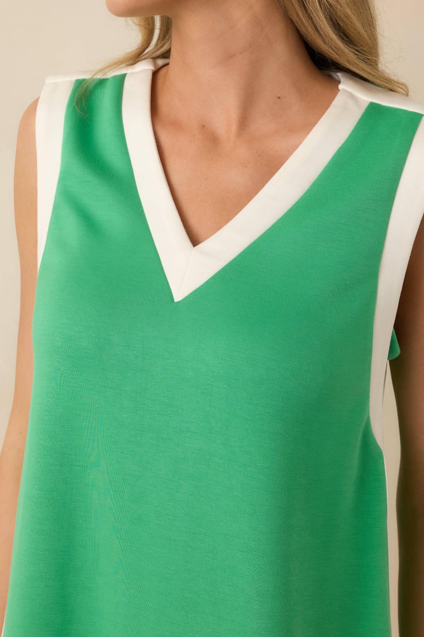Close-up of contrast white trim and soft jersey knit texture on the green mini dress.