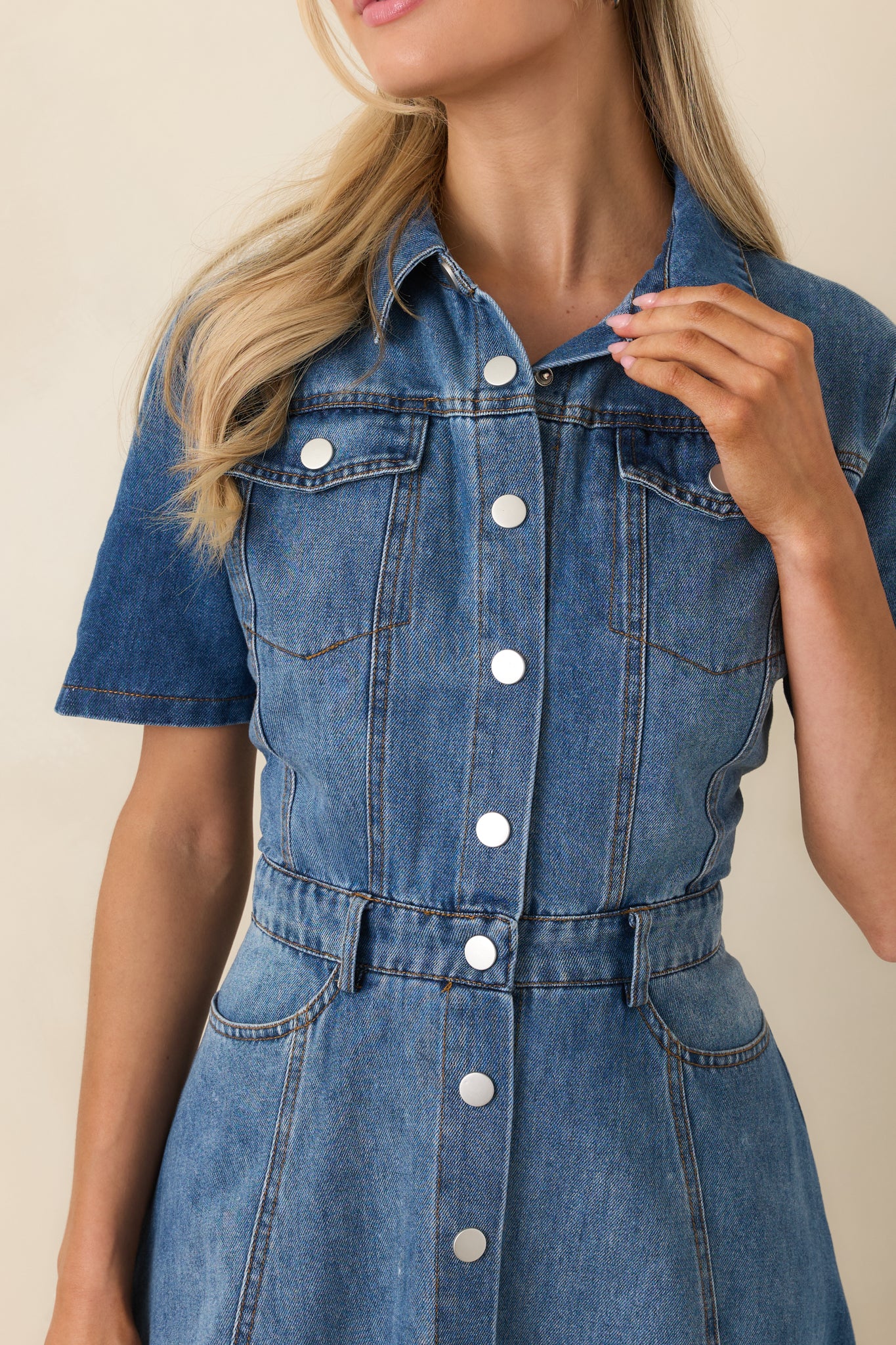 Close-up of cotton denim dress showing snap-button front closure, structured stitching, and durable fabric texture